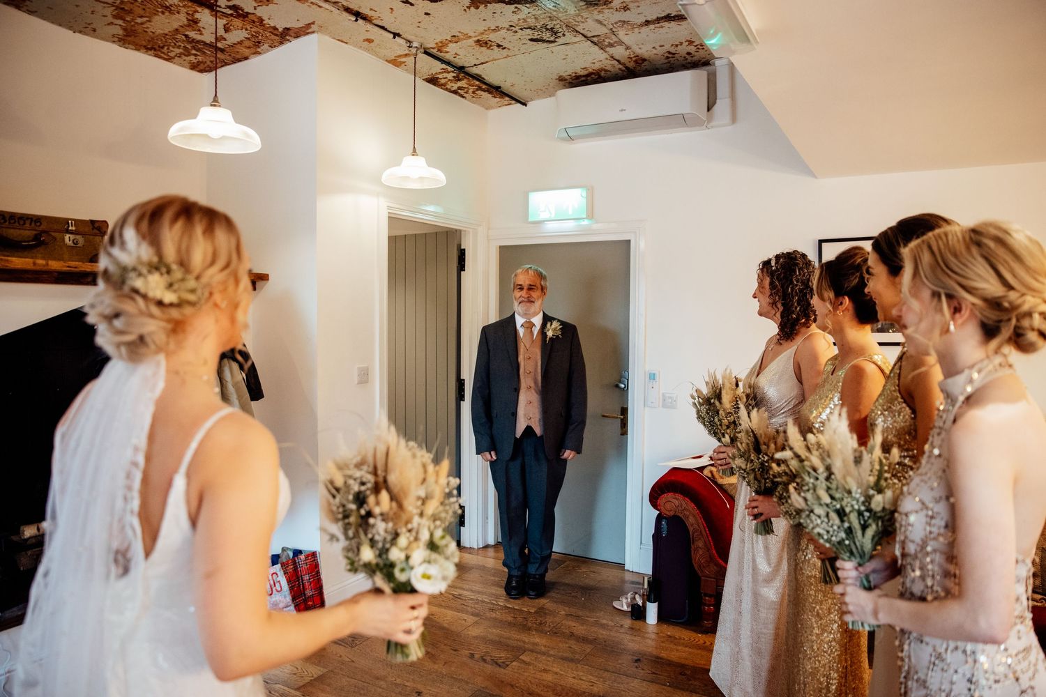 Wedding party getting ready in a rustic room with exposed brick walls and pendant lighting.