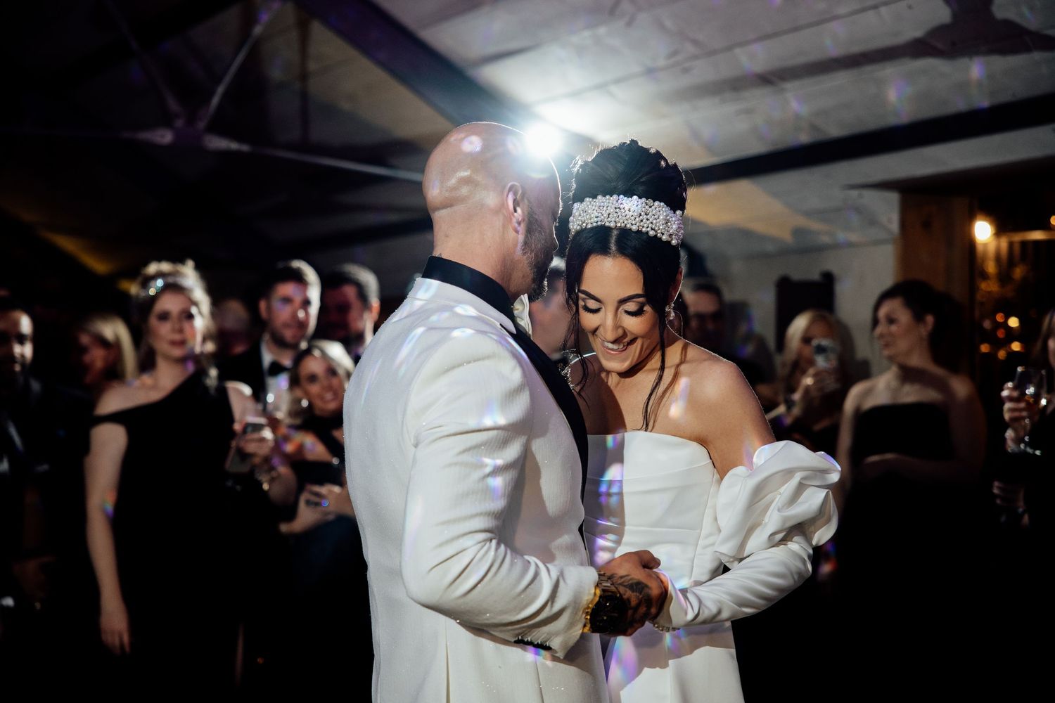 Wedding celebration in a dimly lit reception space with couples dancing on the dance floor.