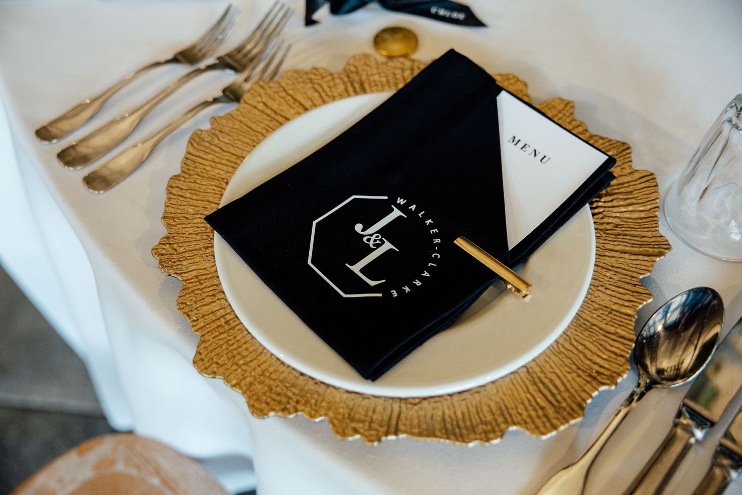 Elegant table settings with gold charger plates and black menu cards create a luxurious dining atmosphere.
