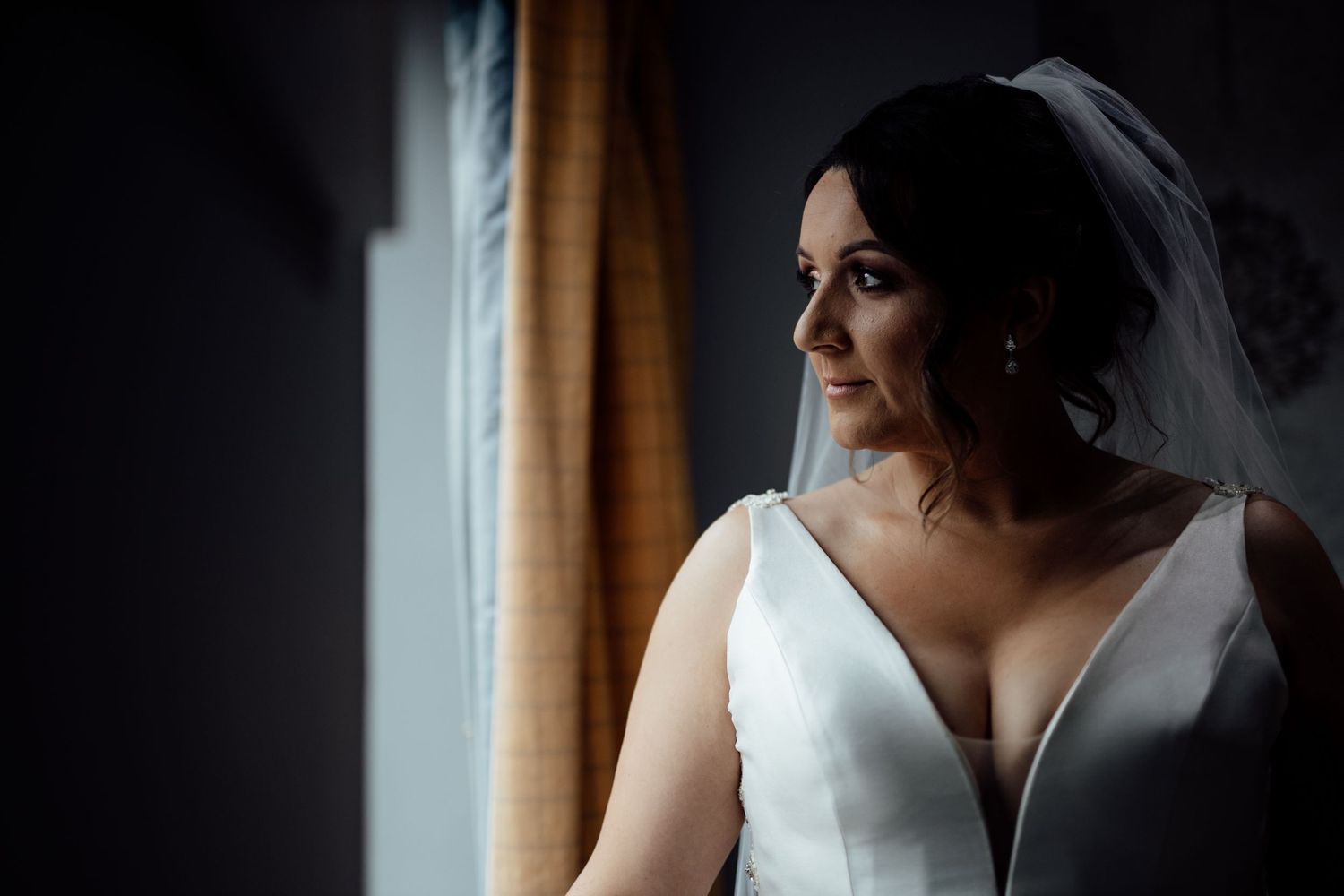 Elegant bridal portrait by window light featuring a classic white wedding dress.
