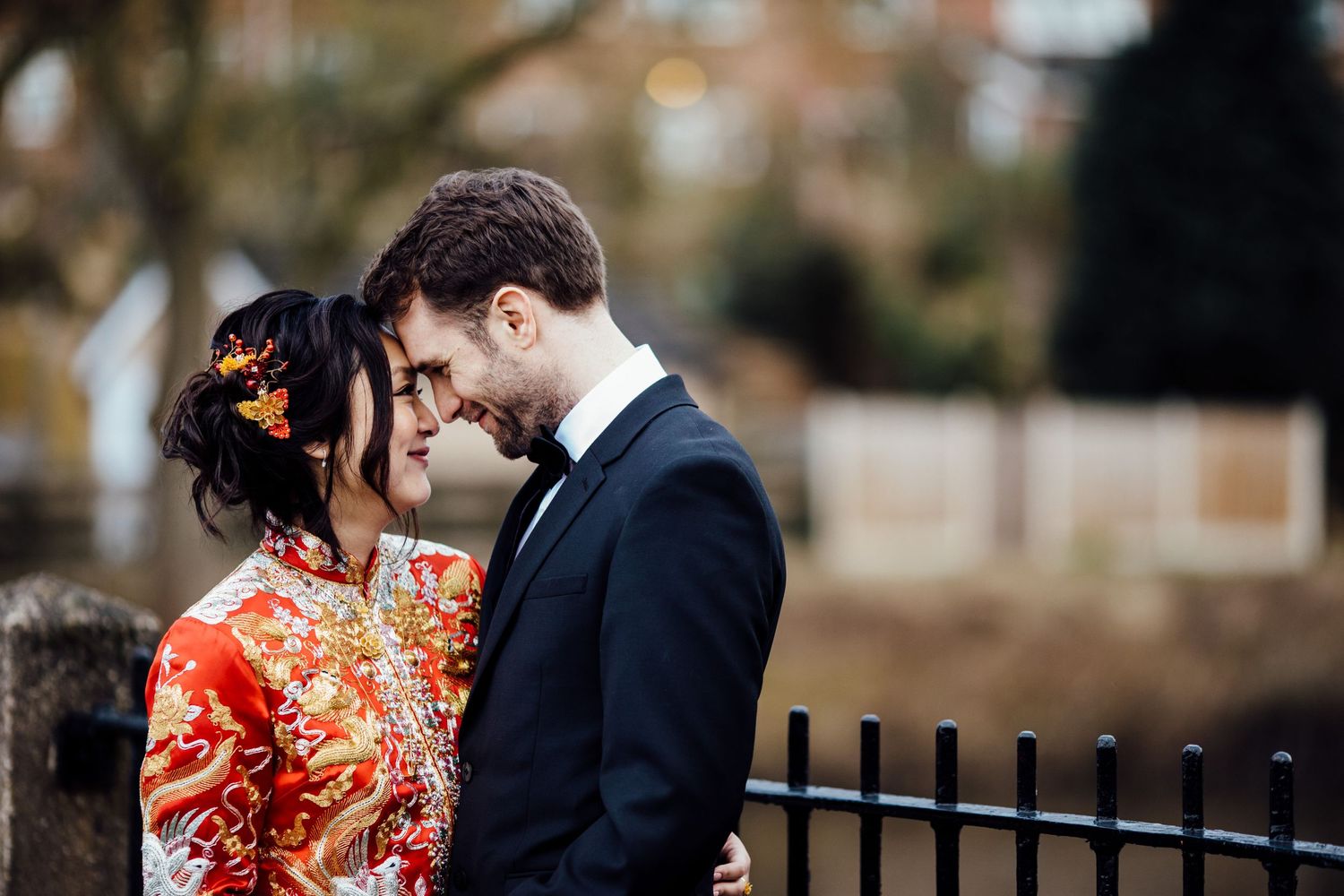 Intimate moment between newlyweds, with bride wearing traditional red Chinese wedding dress.