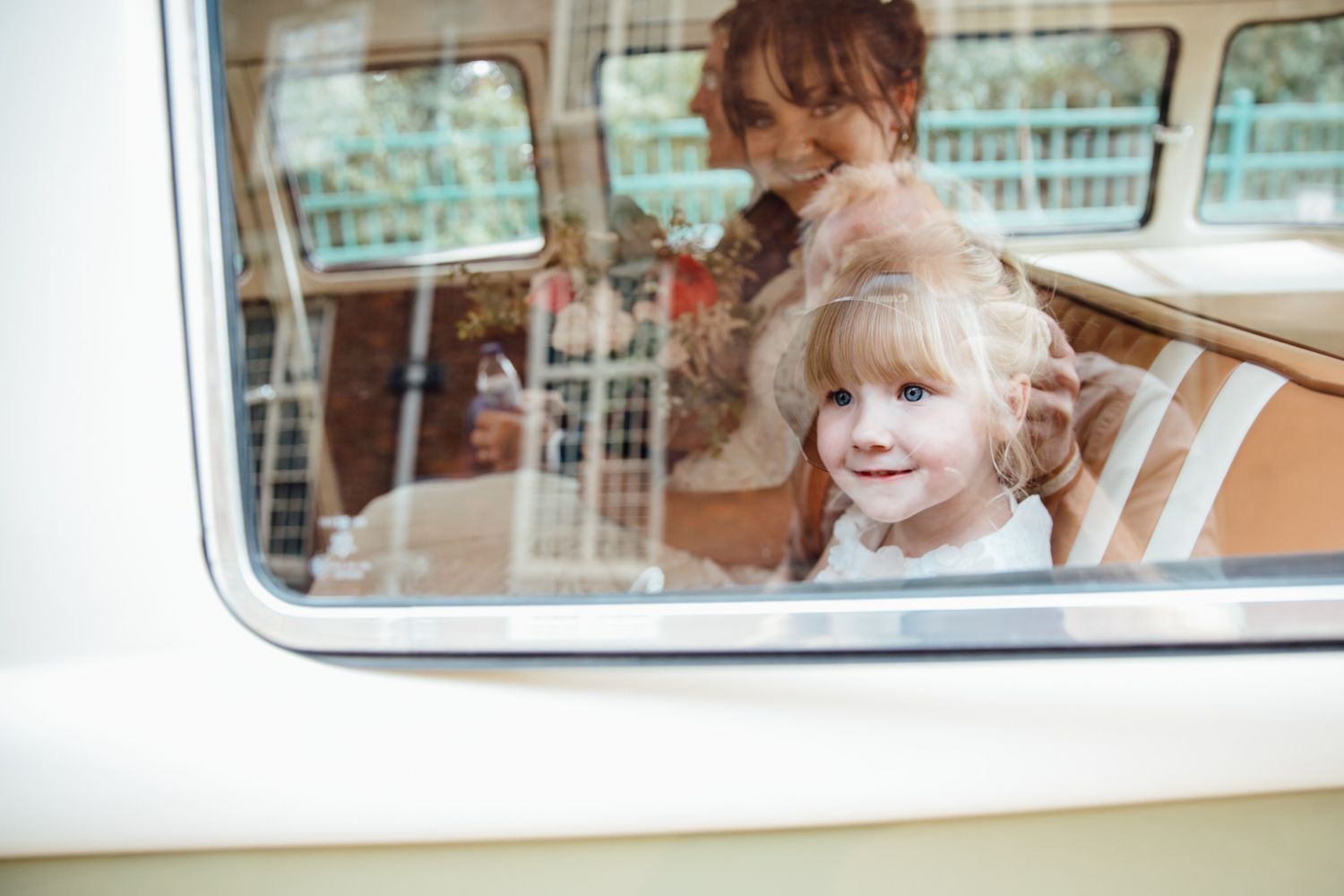 Children looking out the window of a vintage white wedding car.