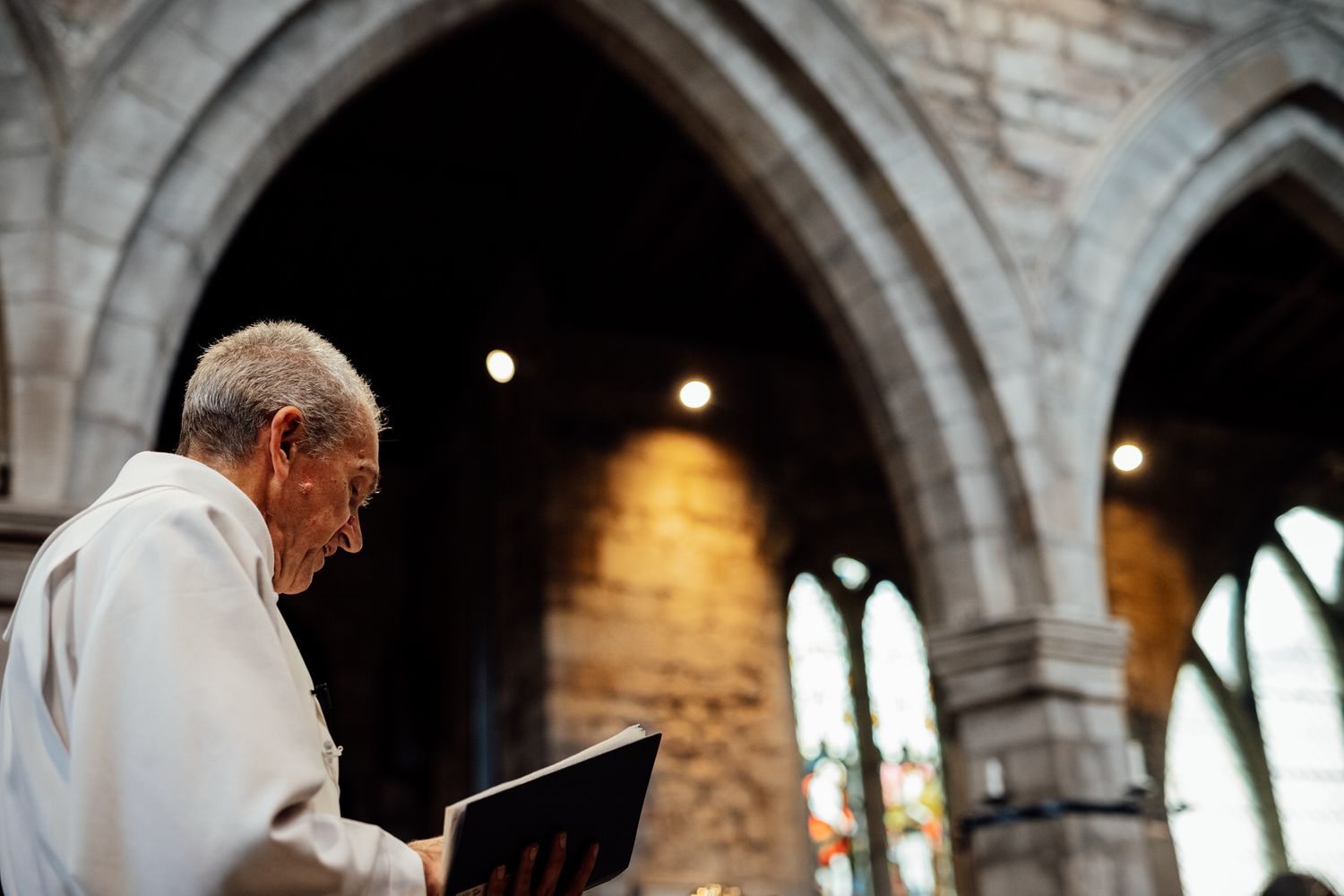 Wedding ceremony taking place under gothic stone arches in a traditional church setting.