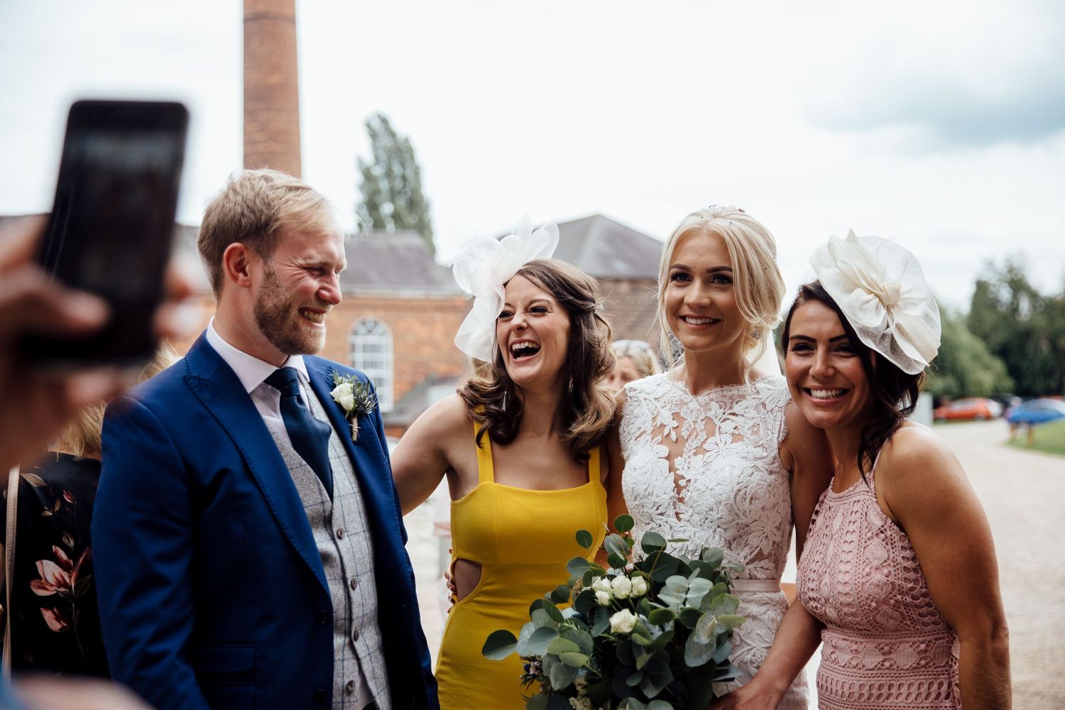 Wedding guests celebrating outside brick venue on sunny day.