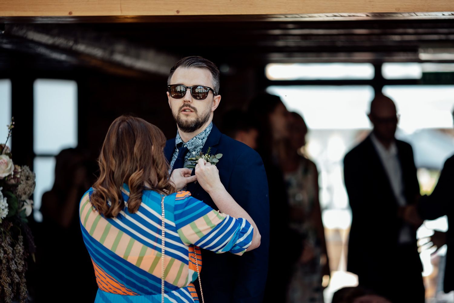 A couple embraces during an indoor wedding ceremony with wooden beams visible in the background.