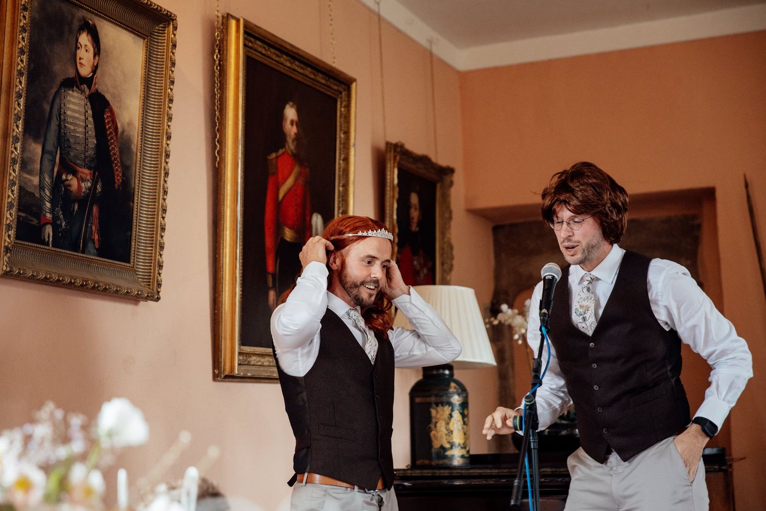 Wedding party getting ready in a warm-toned room with framed portraits on the wall.