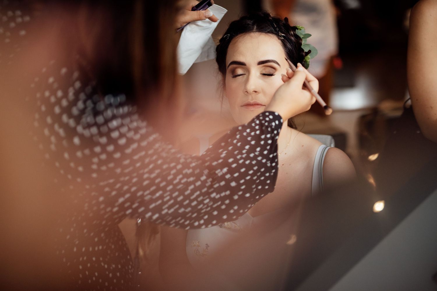 Intimate wedding preparation moments captured through artistic bokeh lighting effects.