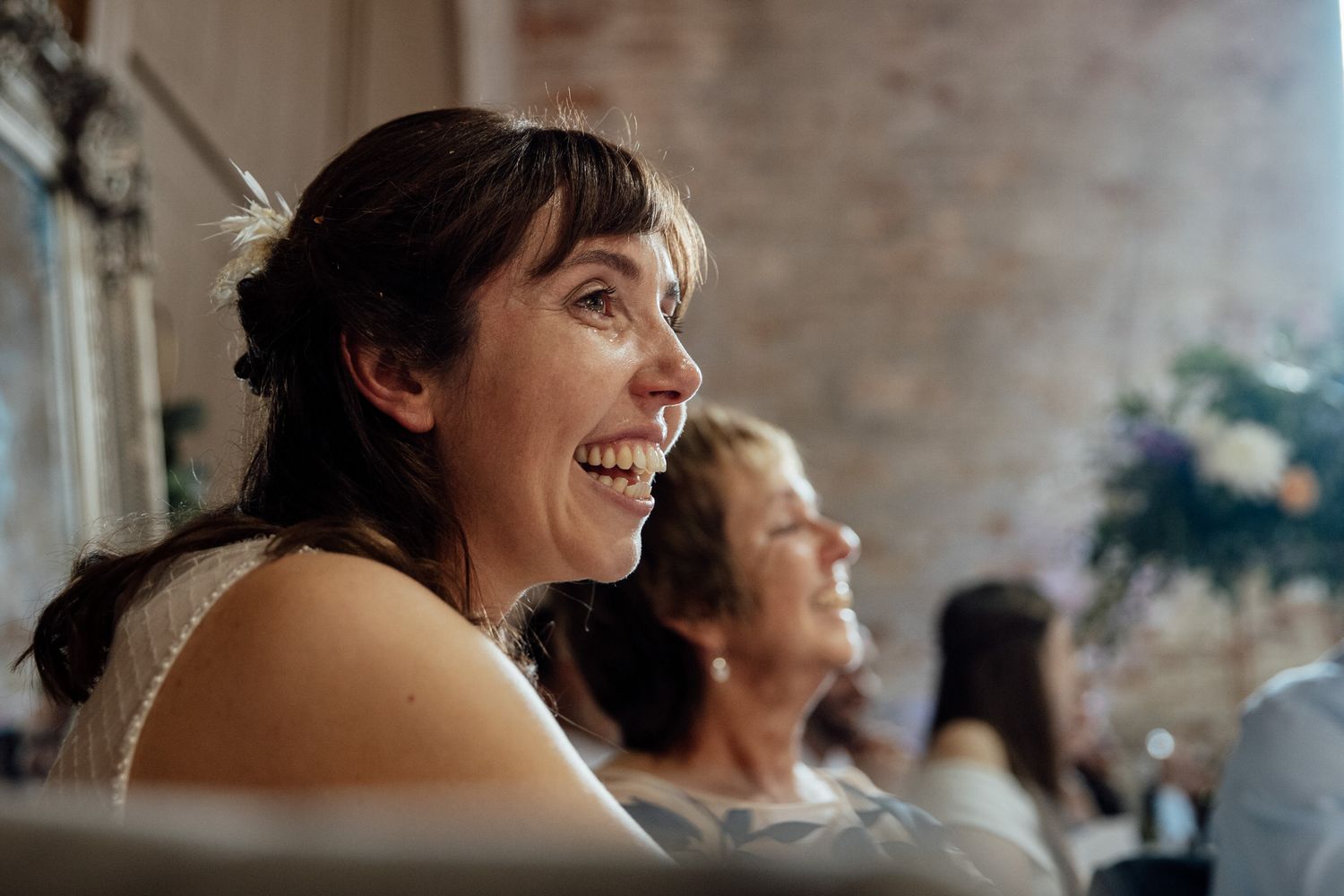 Candid moments of joy captured during wedding celebration with exposed brick backdrop.