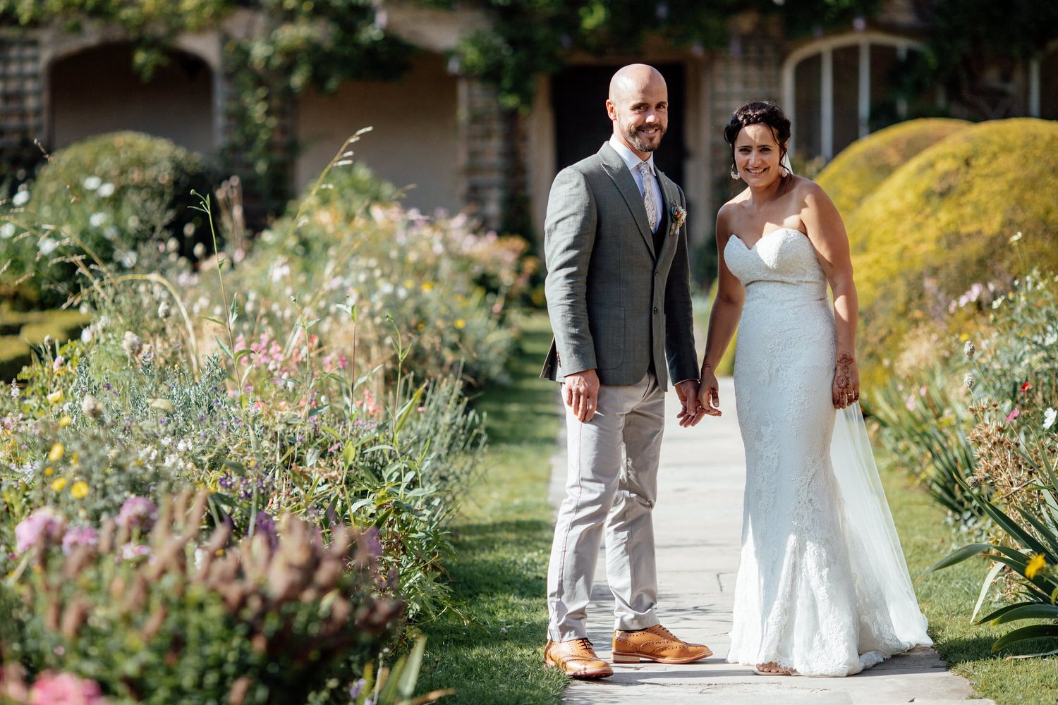 Couple walks together through a lush garden setting on their wedding day.