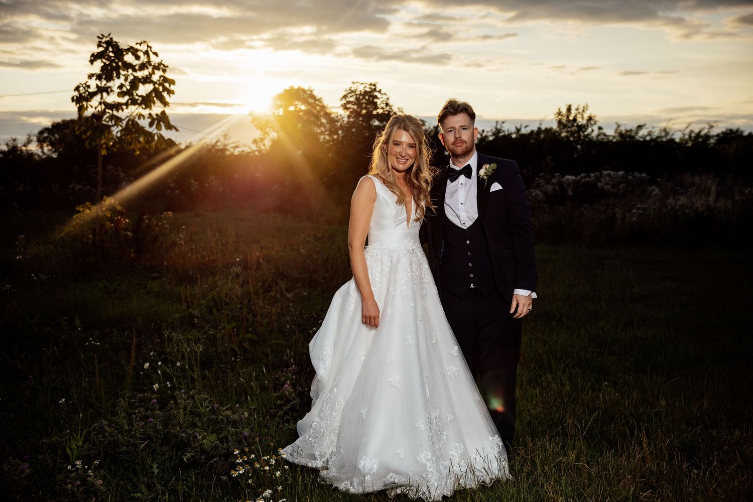 Newlyweds walk hand in hand during golden hour sunset photoshoot.