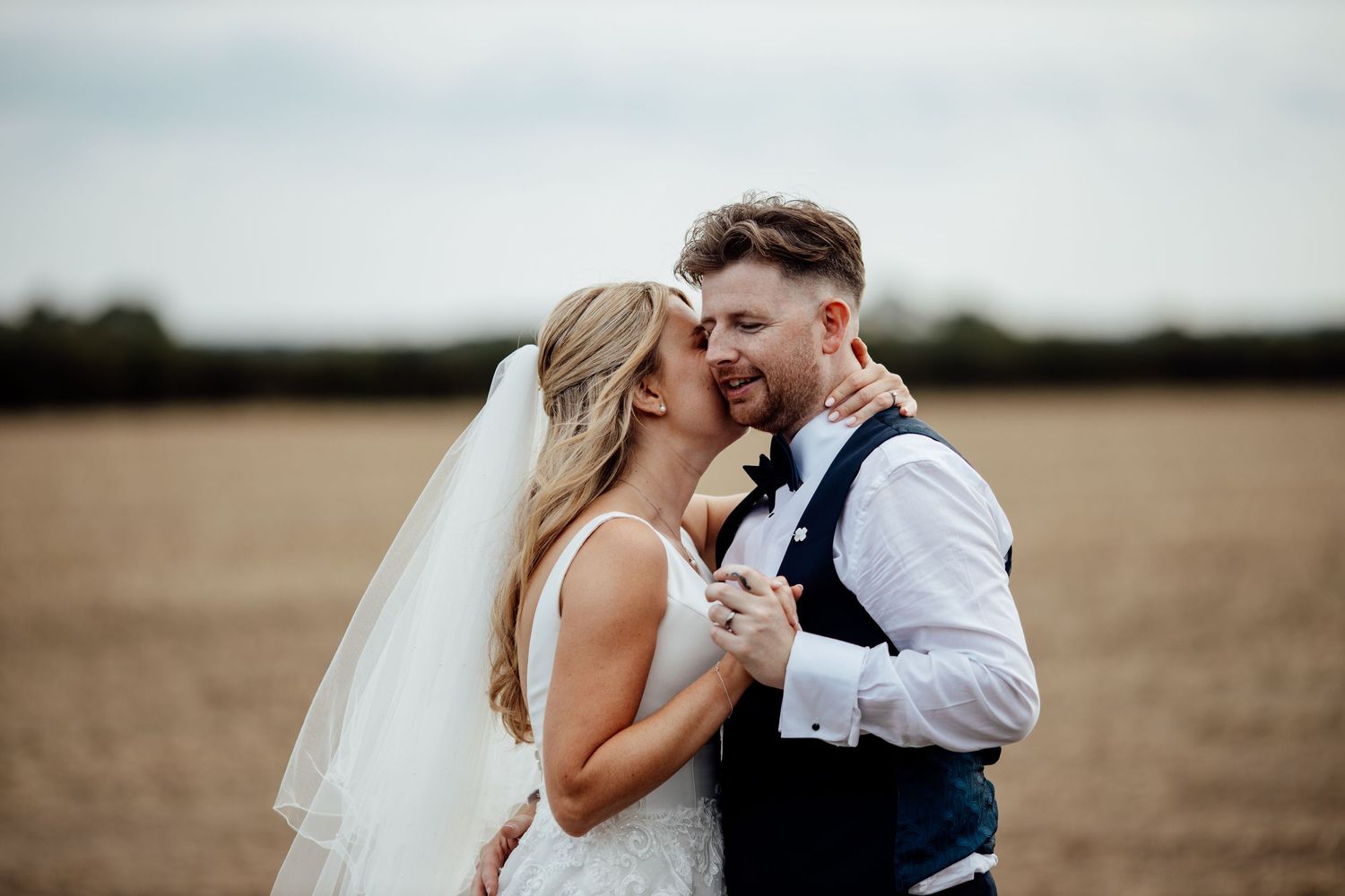 Romantic wedding portraits captured in an open field during sunset.