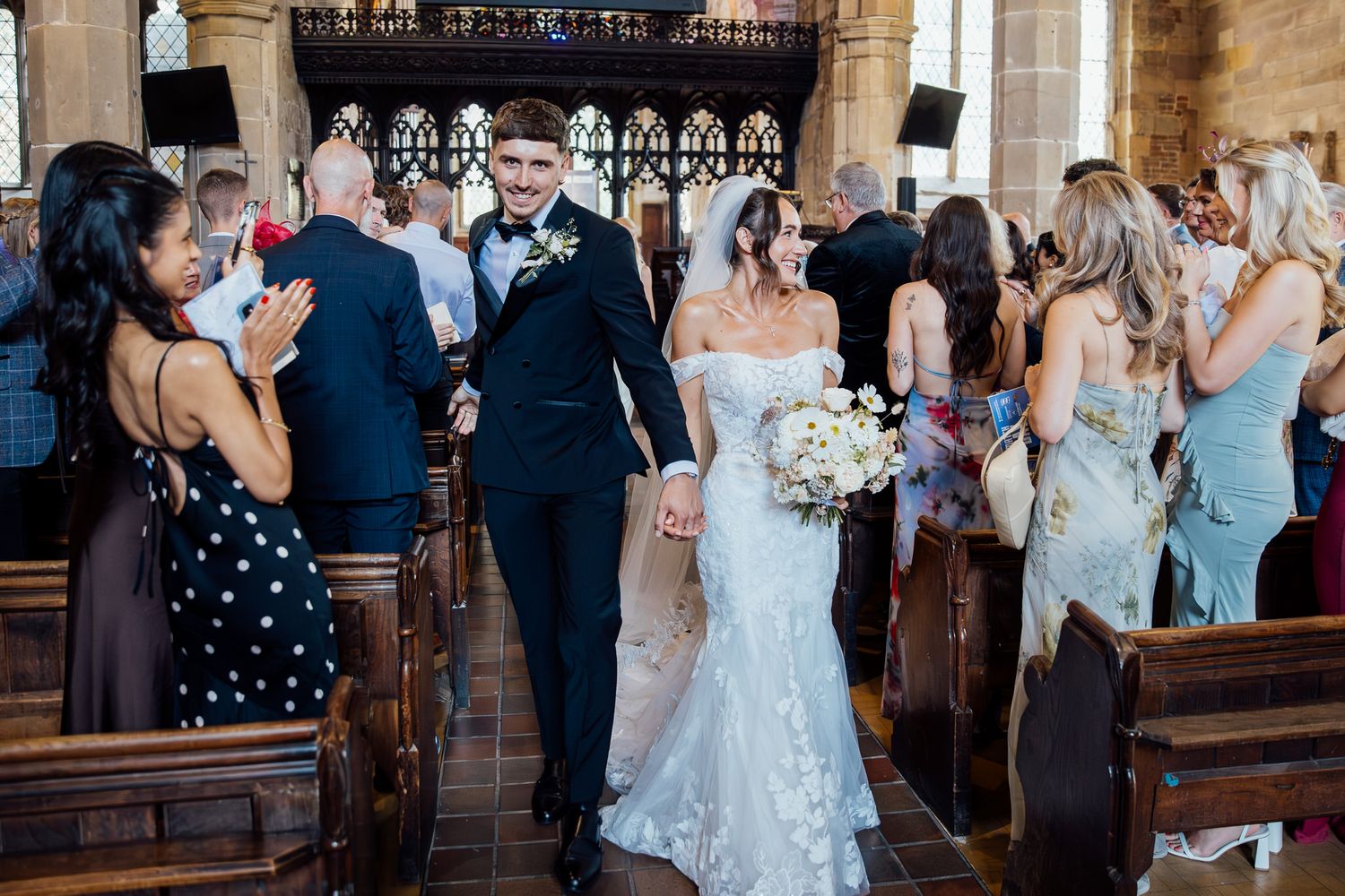 Wedding ceremony guests celebrate joyfully inside historic stone church with ornate architecture.