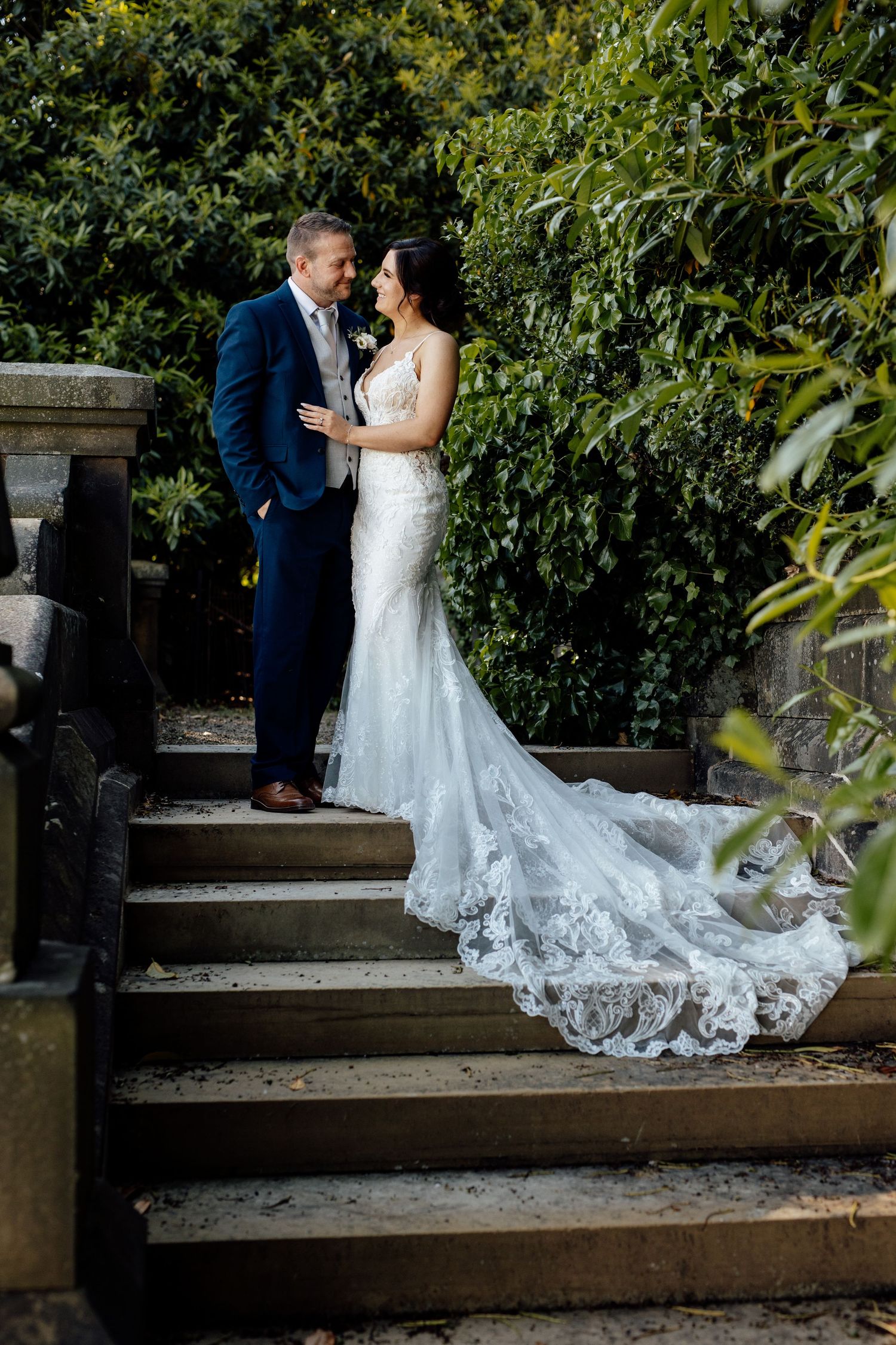 Couple shares an intimate moment on a rustic wooden bench surrounded by greenery.