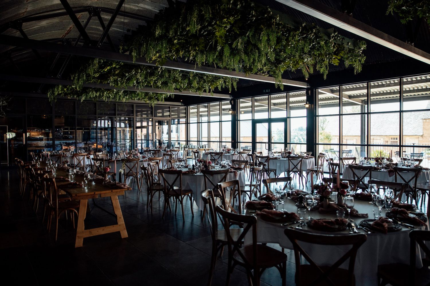 Modern wedding reception venue with elegant table settings and natural light streaming through windows.