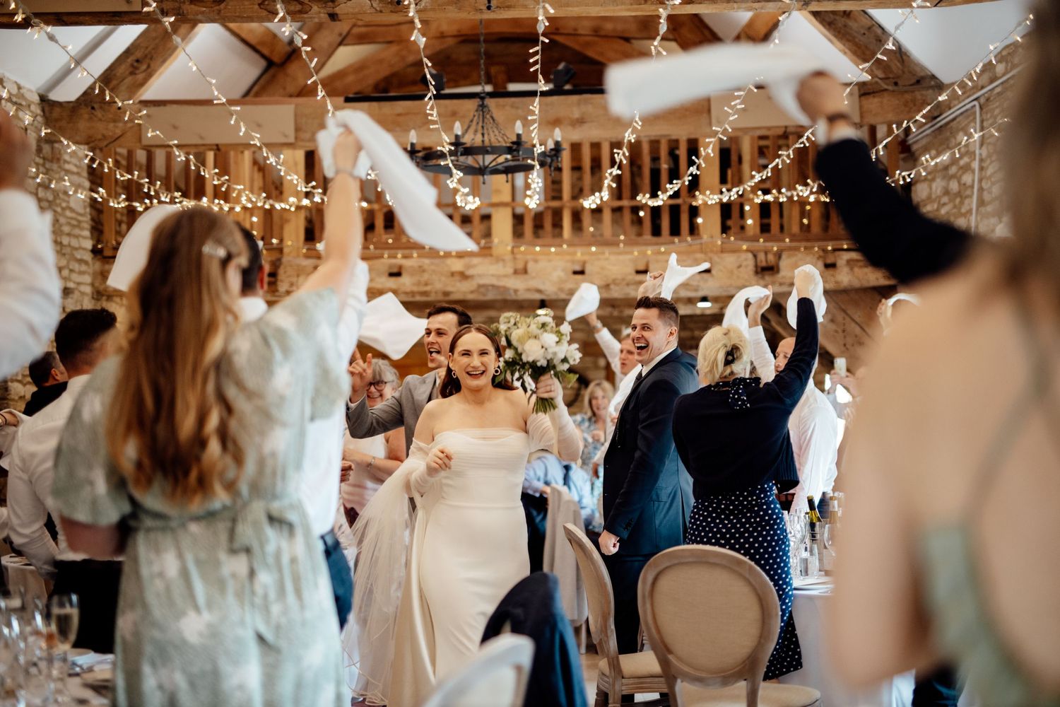 Wedding reception dance floor filled with guests celebrating under hanging string lights.