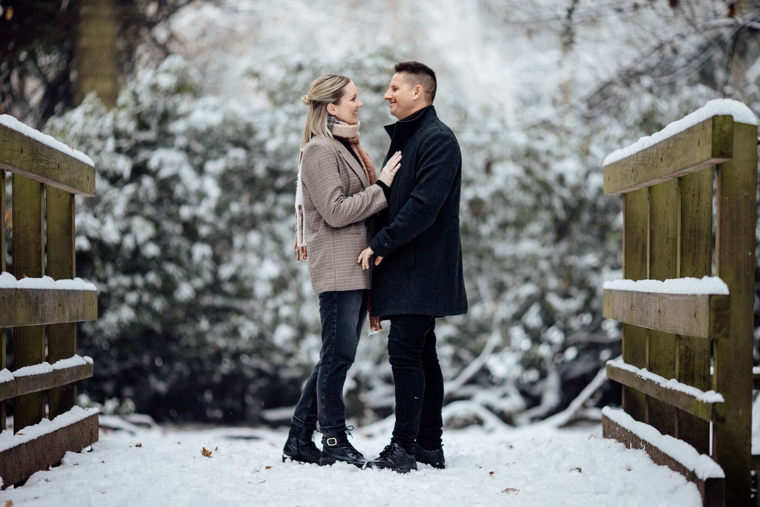 A romantic winter scene on a snow-covered wooden bridge surrounded by frosty trees.