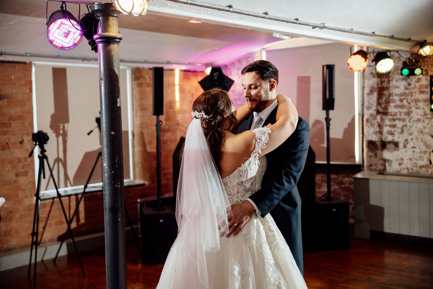 Wedding reception moments captured in a rustic venue with exposed brick walls and mood lighting.
