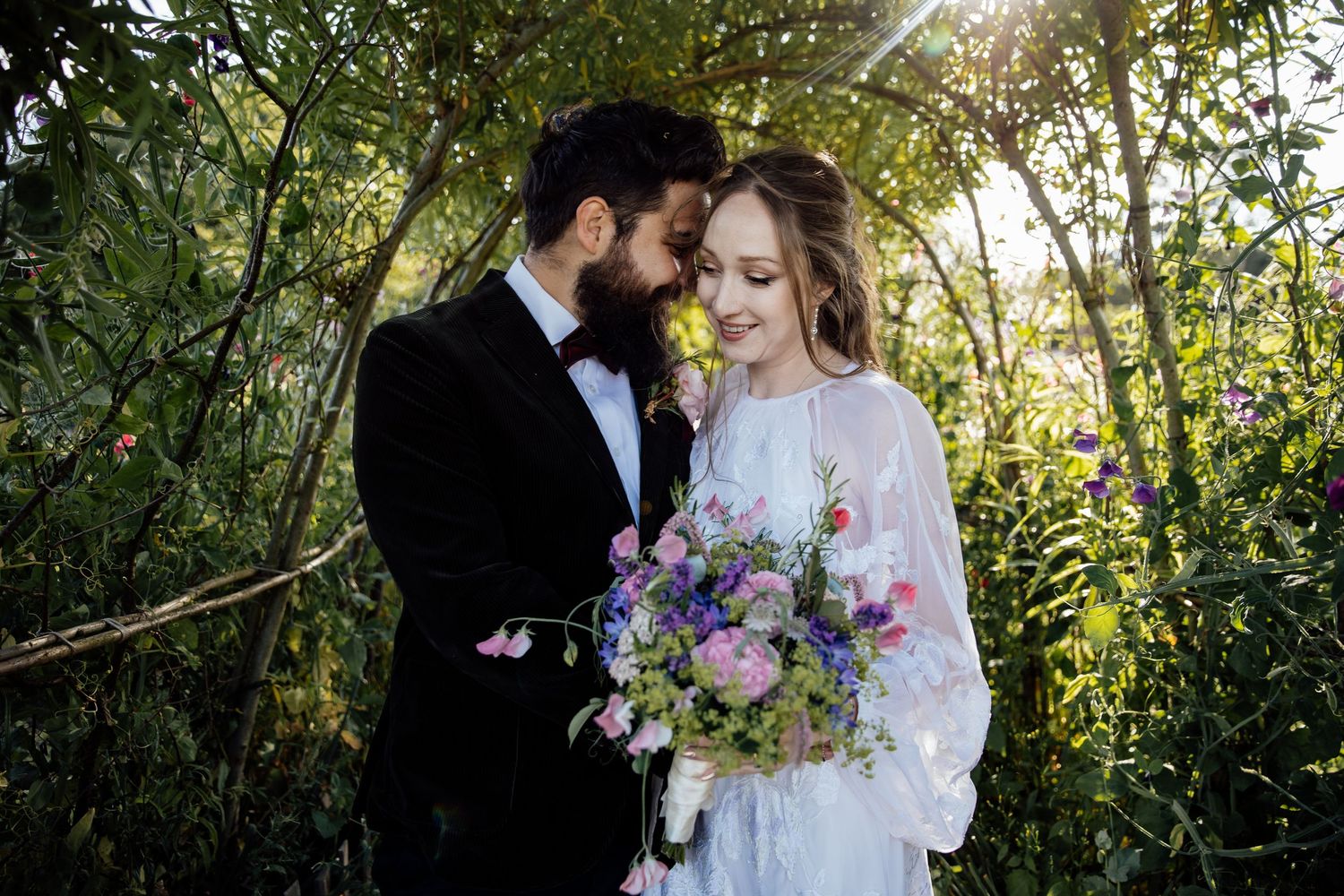 Romantic wedding photos captured in golden sunlight among blooming flowers and greenery.