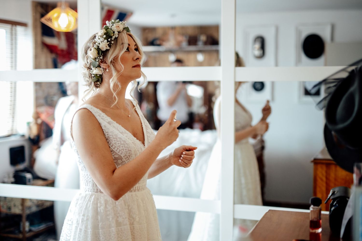A person in a white dress gestures expressively in a room with mirrors.