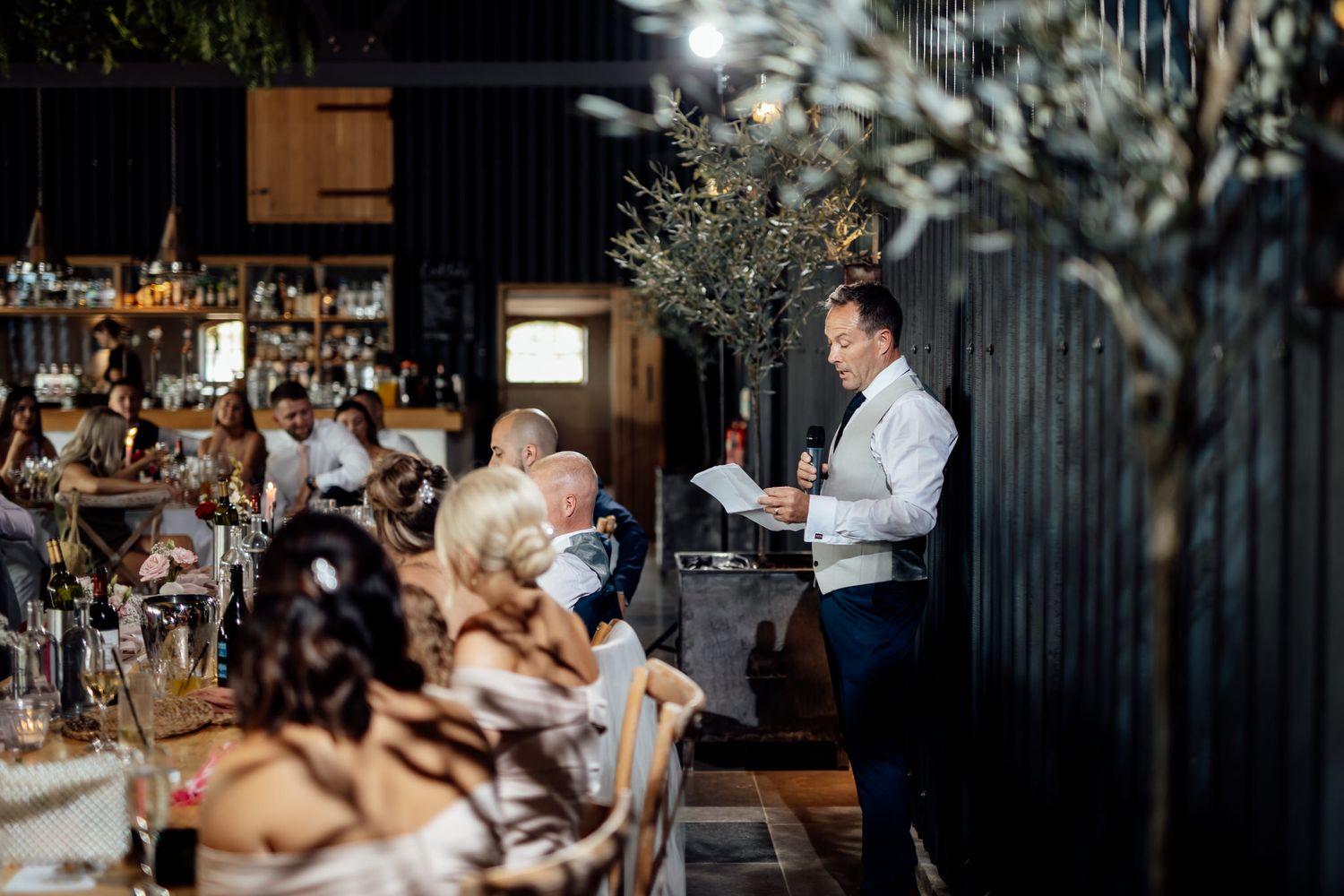 Candid reception moments captured in moody lighting at rustic indoor venue.
