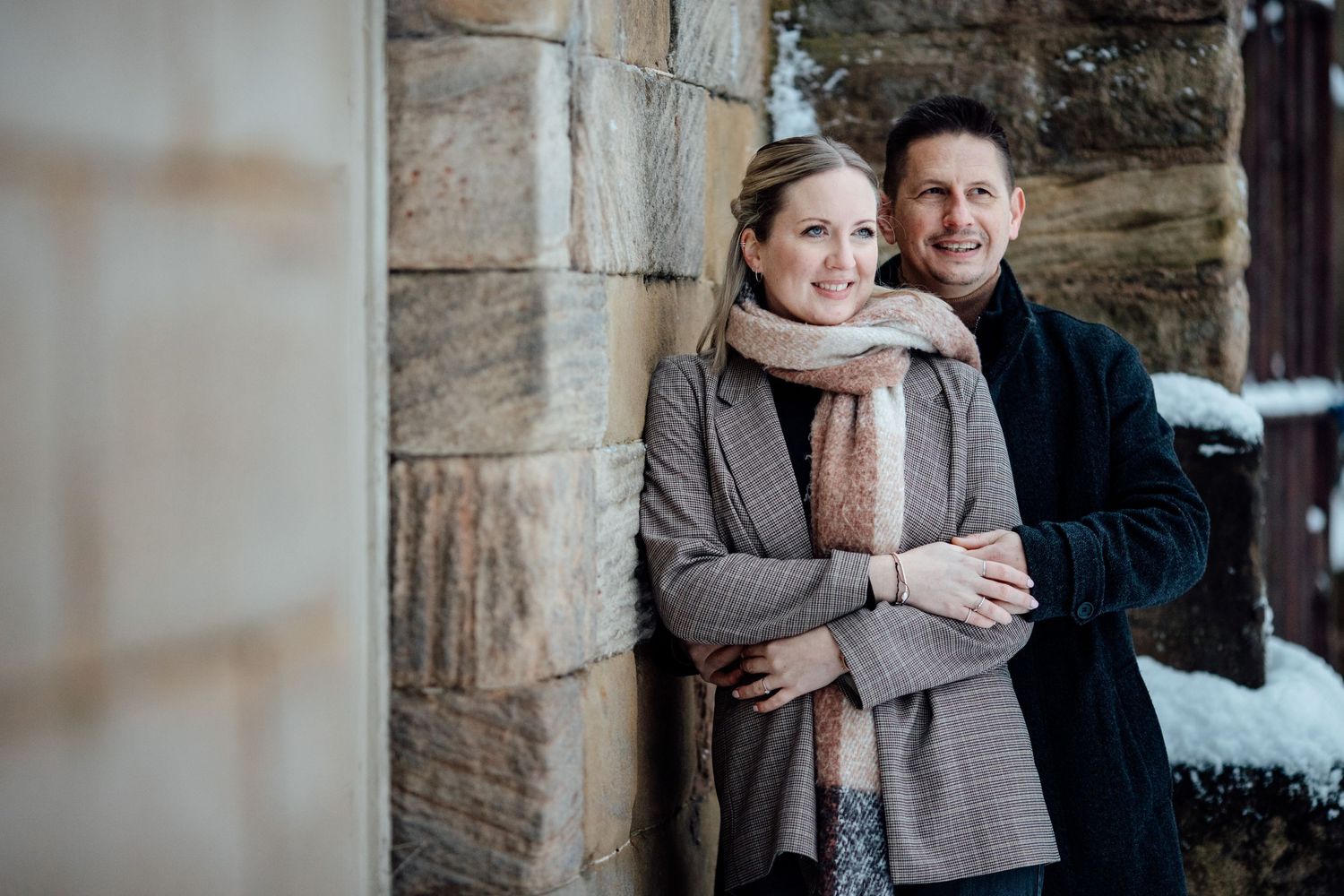 Winter engagement session featuring exposed brick architecture and natural snow.