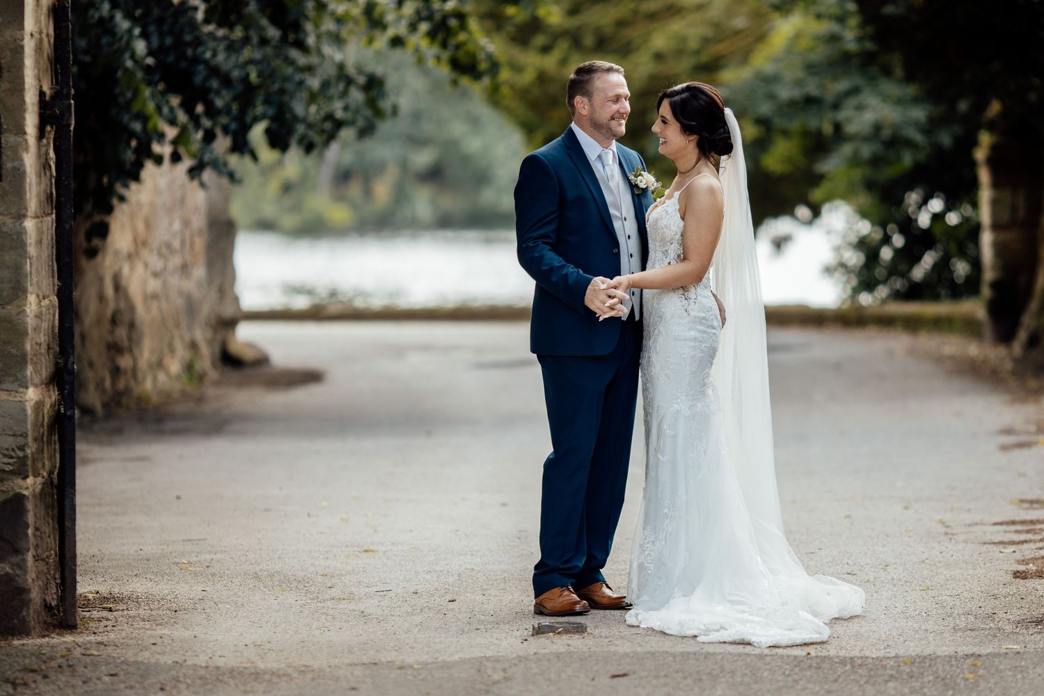 A romantic wedding portrait on a tree-lined path.