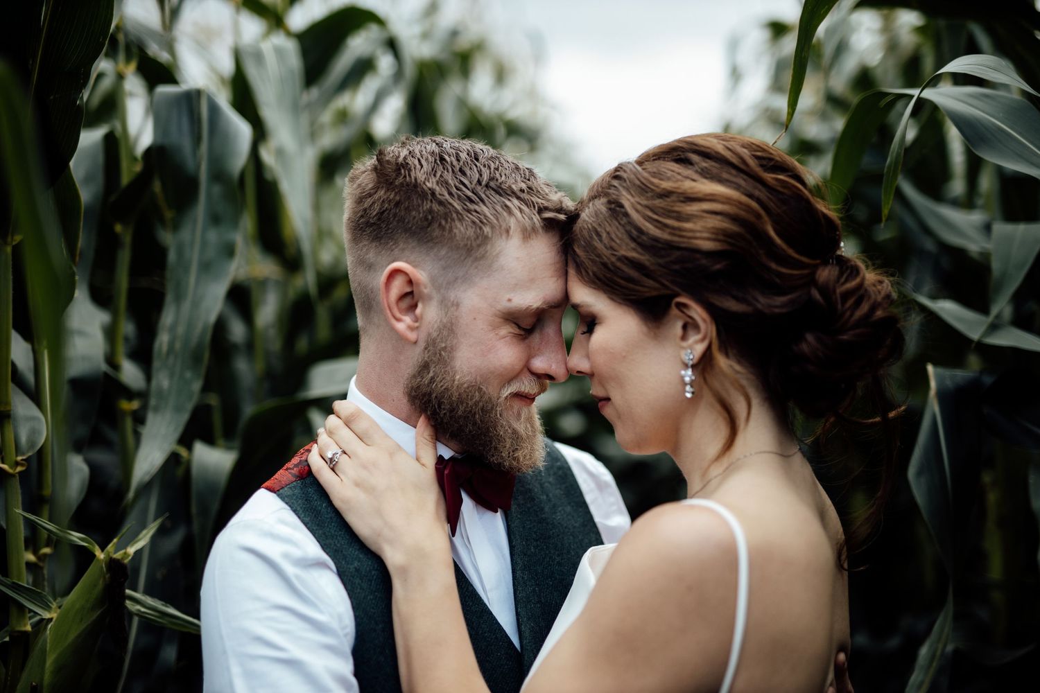 Romantic couple shares intimate moments in a cornfield during a wedding photoshoot.