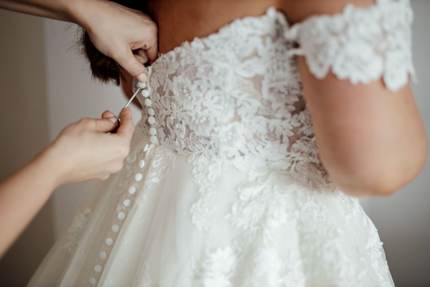 Close-up details of delicate lace and beading on a white wedding dress.