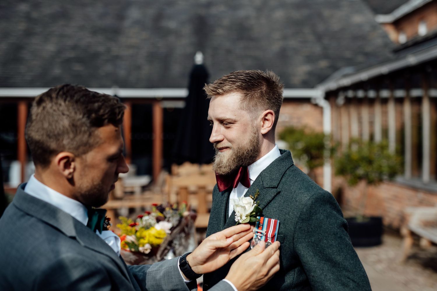Groomsmen sharing a toast outdoors near brick buildings.