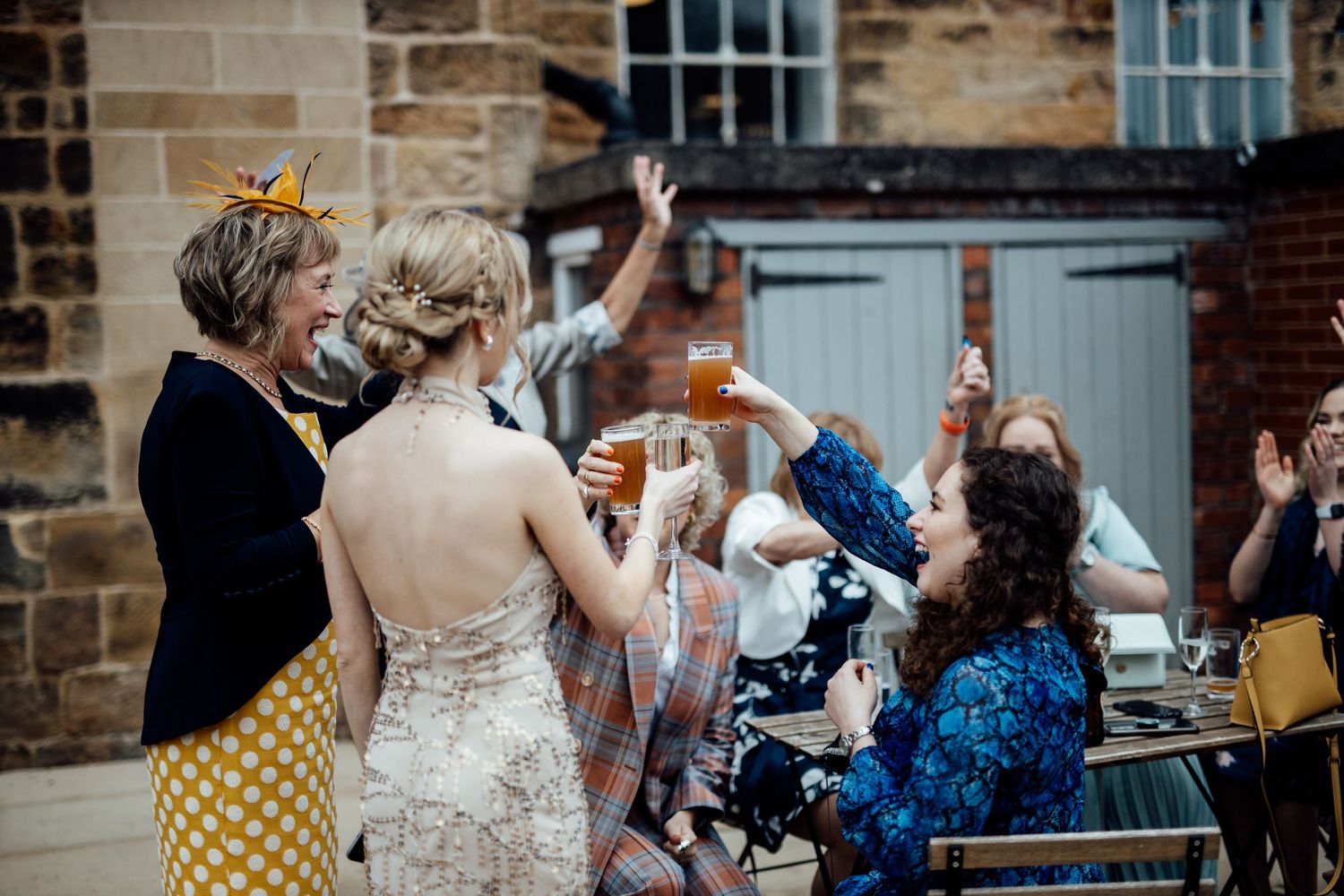 Wedding guests dancing and celebrating in front of historic stone building exterior.