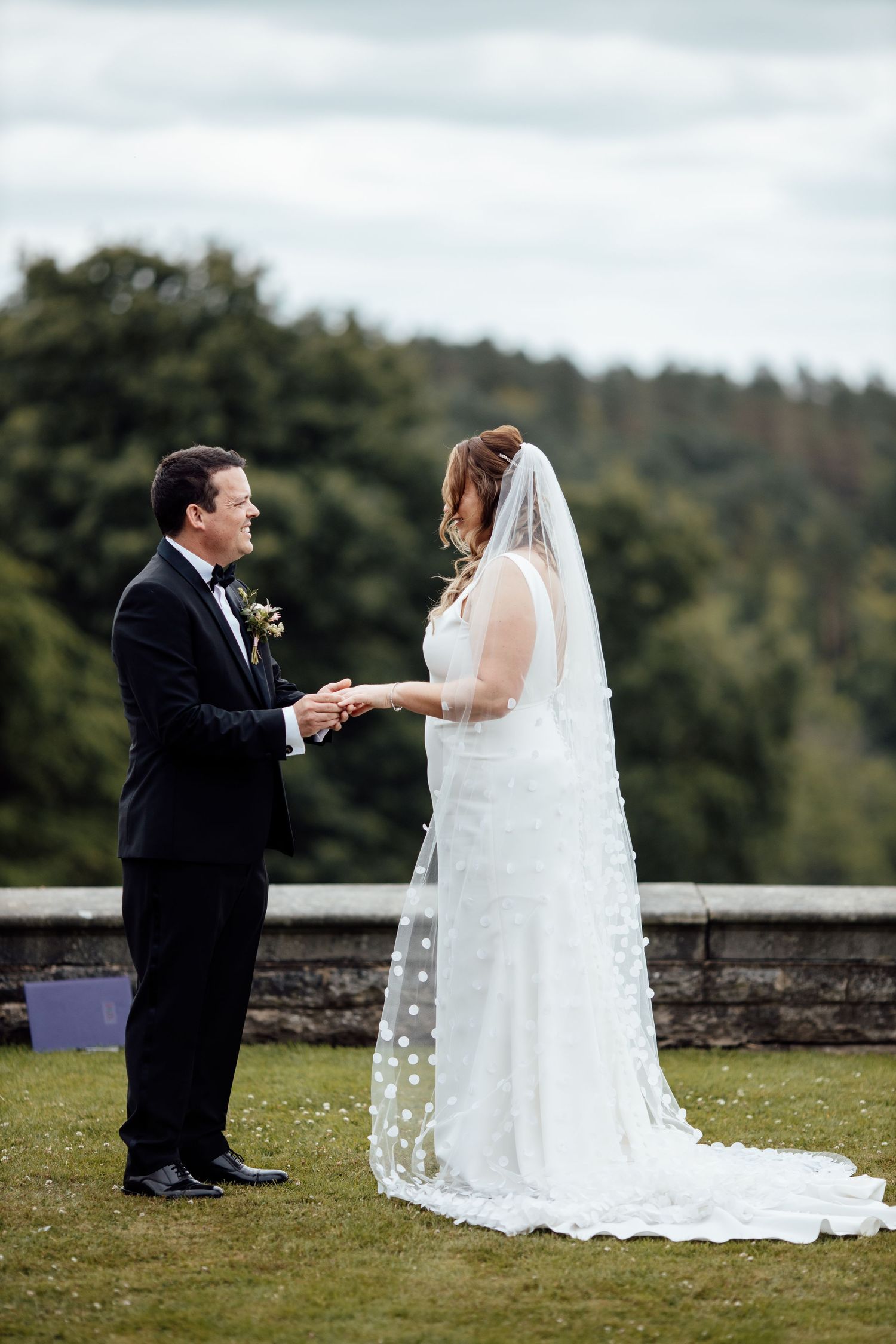 Wedding ceremony moment on a scenic hilltop with elegant white dress and formal attire.