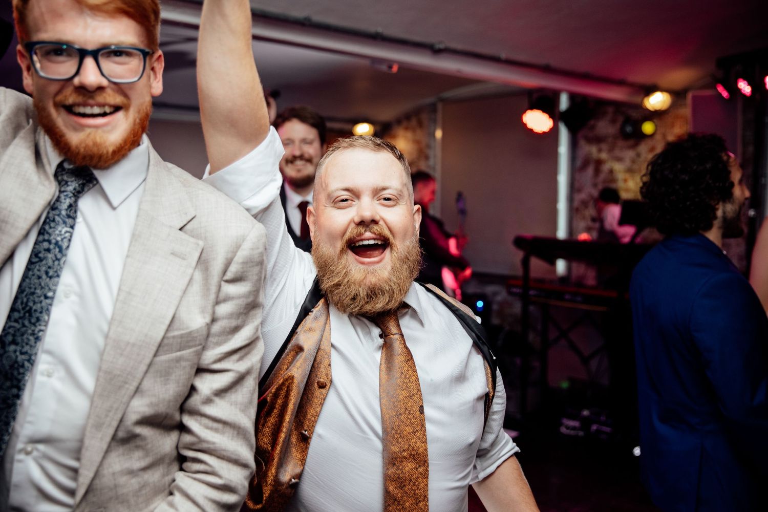 Wedding reception guests enjoying themselves on a dance floor with festive lighting.