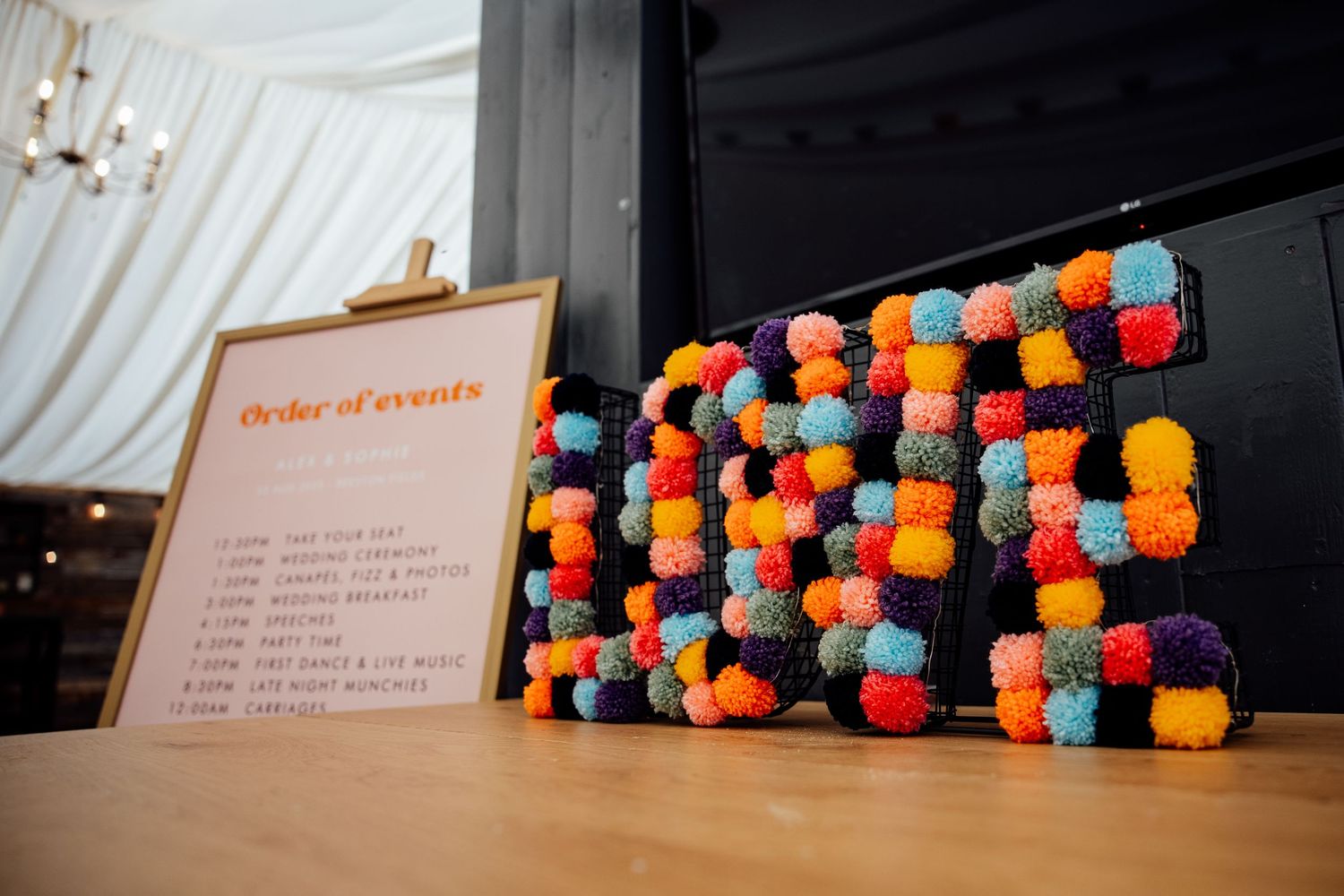 Decorative orange and blue pom pom garland display against white backdrop.
