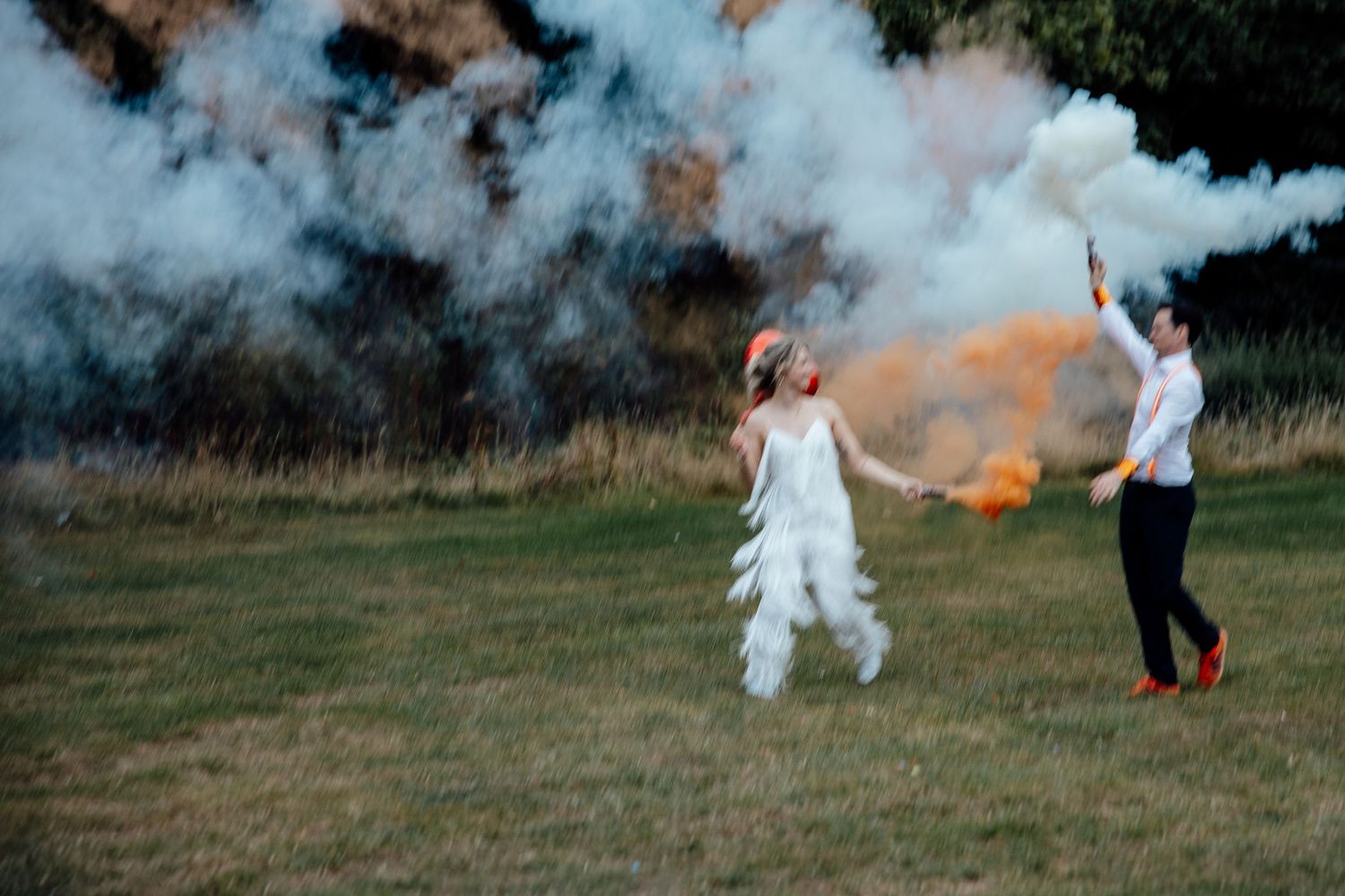 Colorful smoke bombs create dramatic effect in an outdoor wedding photoshoot.