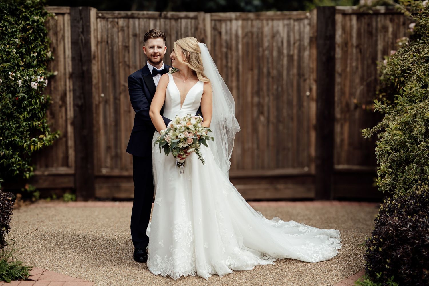 Romantic outdoor wedding photos taken in front of a rustic wooden fence.