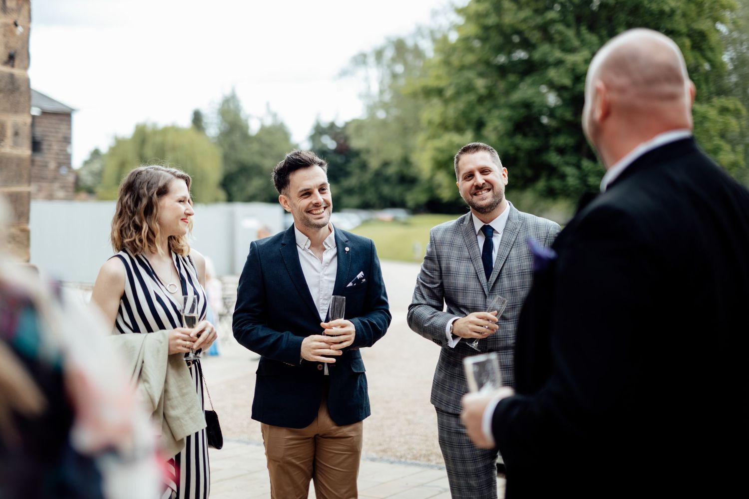 Wedding guests mingling outdoors at a rustic venue during cocktail hour.