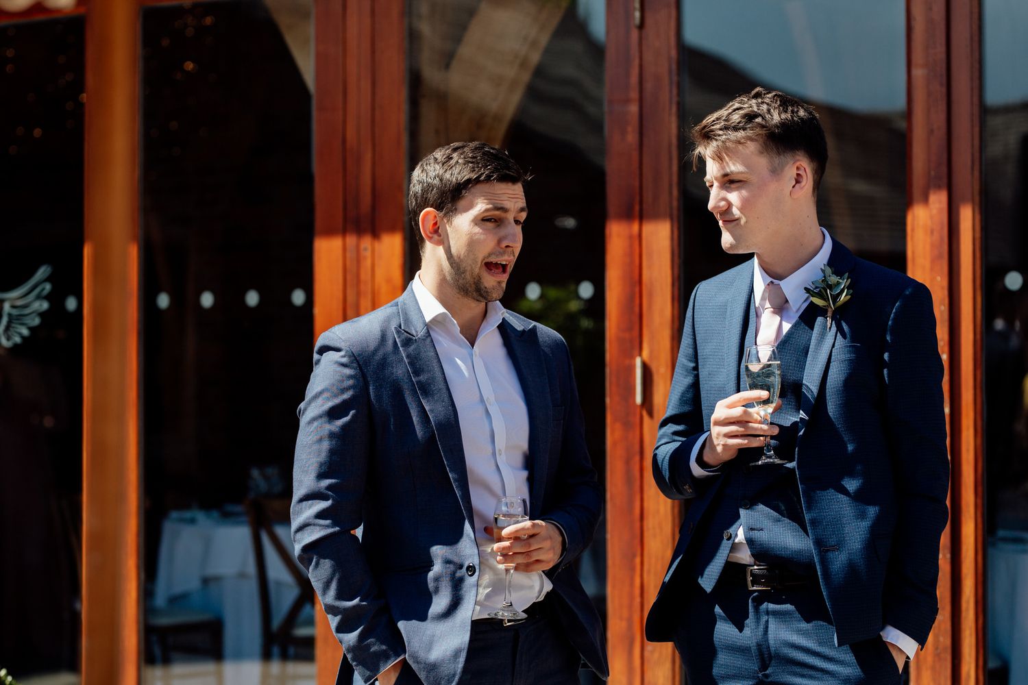 Group in navy suits gathered for drinks on outdoor patio.