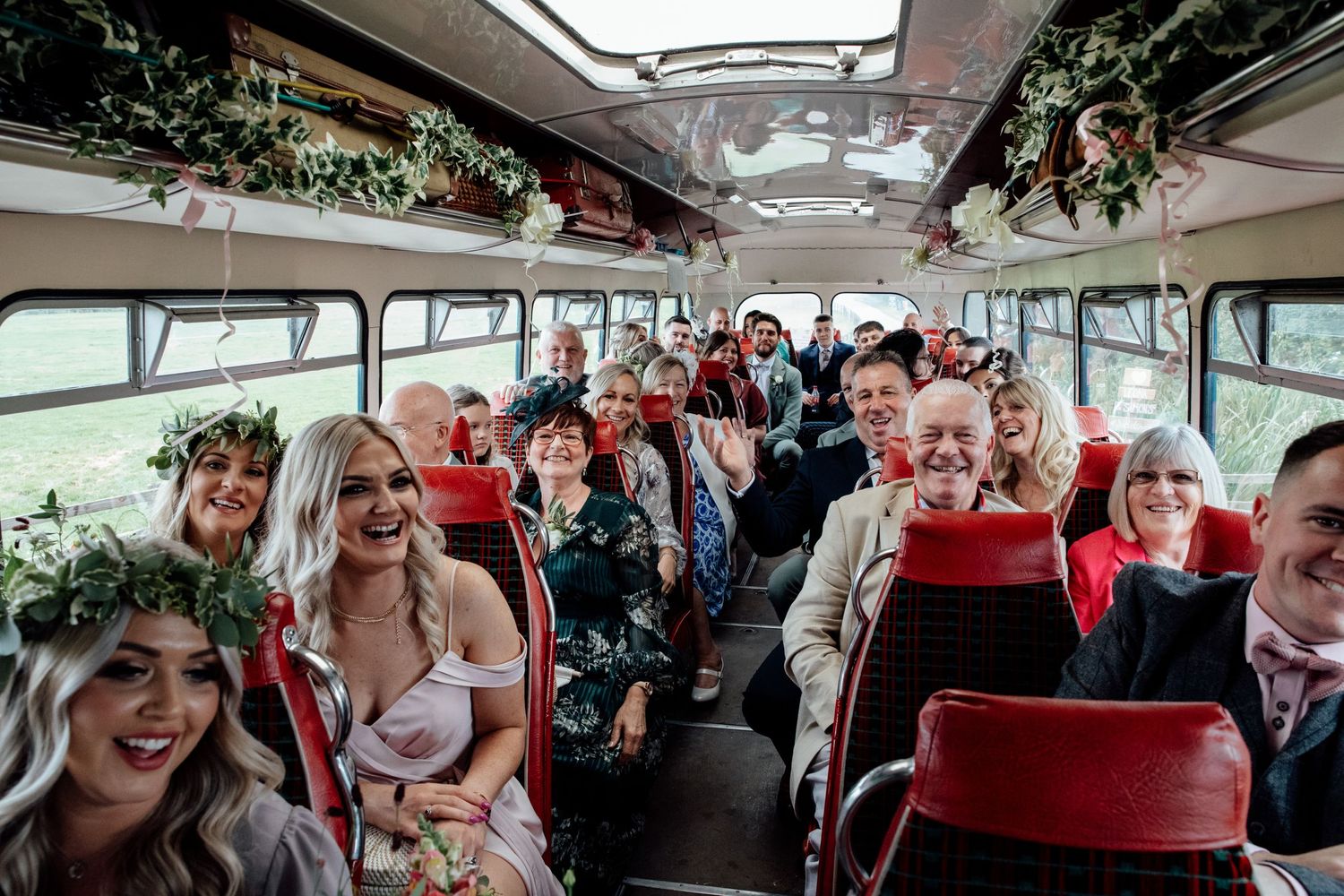 Wedding guests celebrating on a decorated vintage bus during transportation.