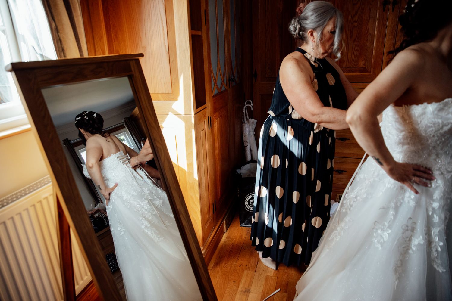 Getting ready moments captured in a warmly lit wooden room with wedding attire.
