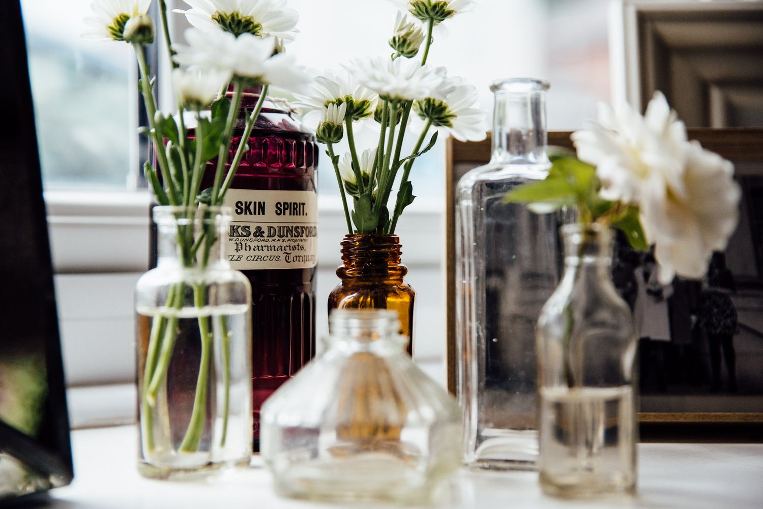 White flowers arranged in clear glass vases on windowsill.