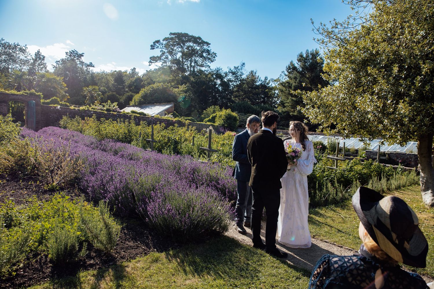 Wedding couple poses in scenic garden setting with blooming lavender fields and natural landscapes.