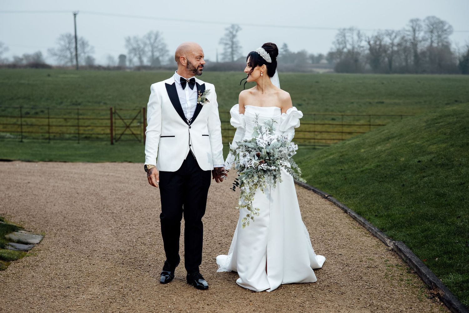 Wedding couple walking together across a scenic countryside landscape.