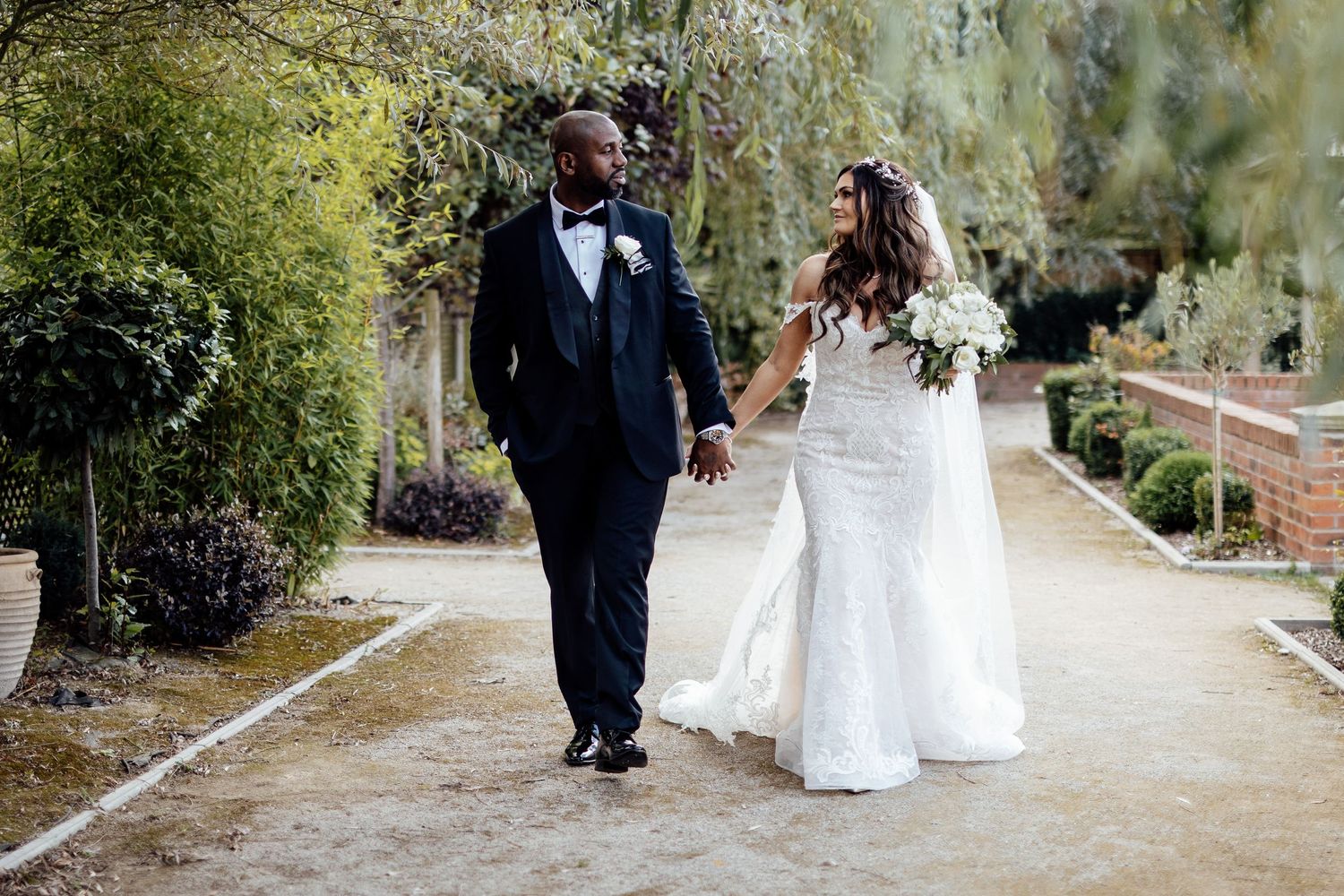 Wedding party walking along garden path during outdoor photo session.