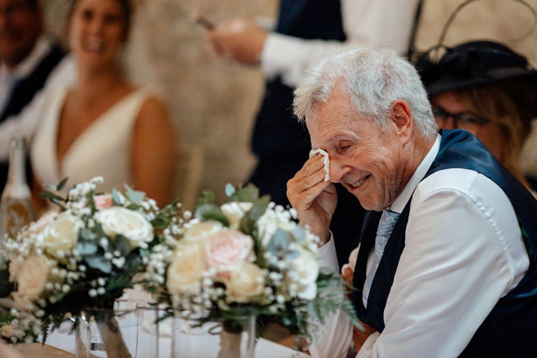 Wedding reception guests seated at tables with elegant white floral centerpieces.