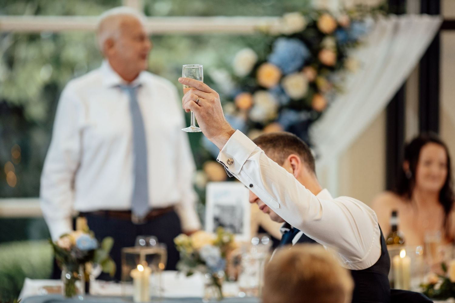 Wedding reception toasts and celebrations with guests raising glasses.