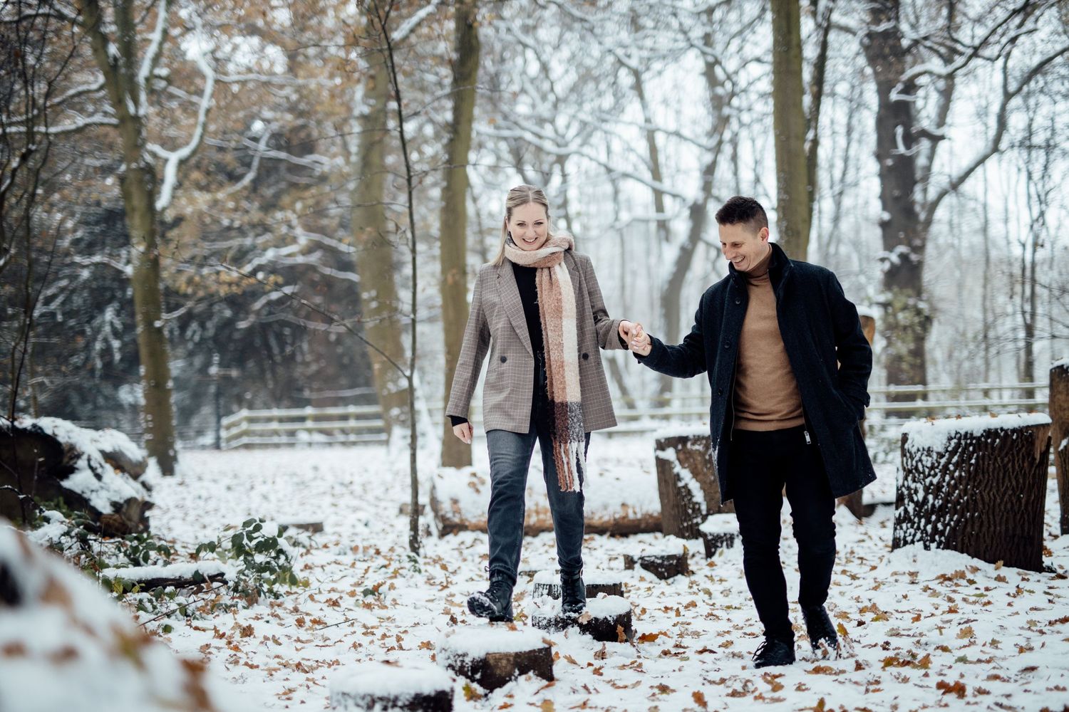Wide angle shot of a winter engagement session in a snow-dusted forest.