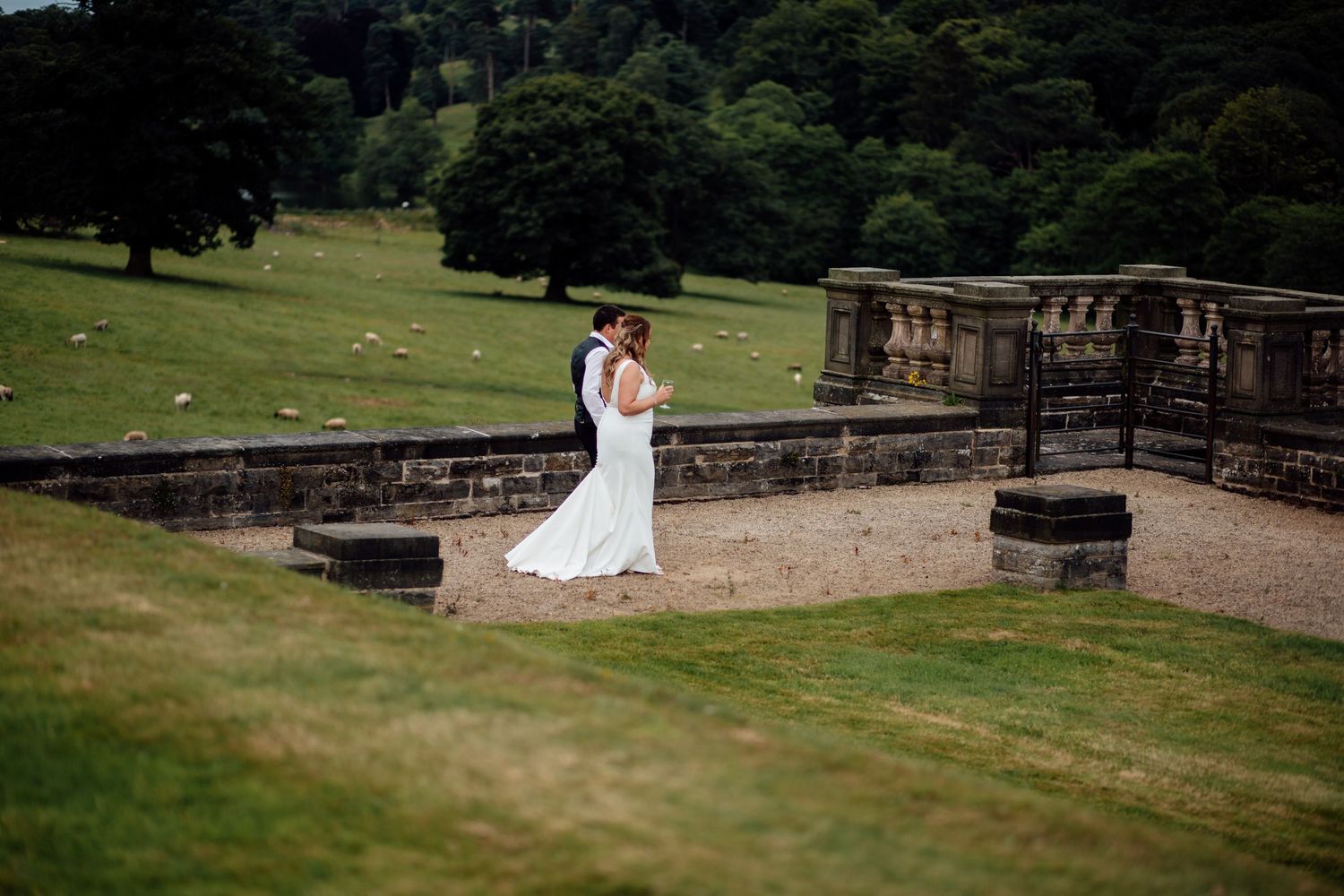 A scenic outdoor wedding venue features stone walls and green lawns.