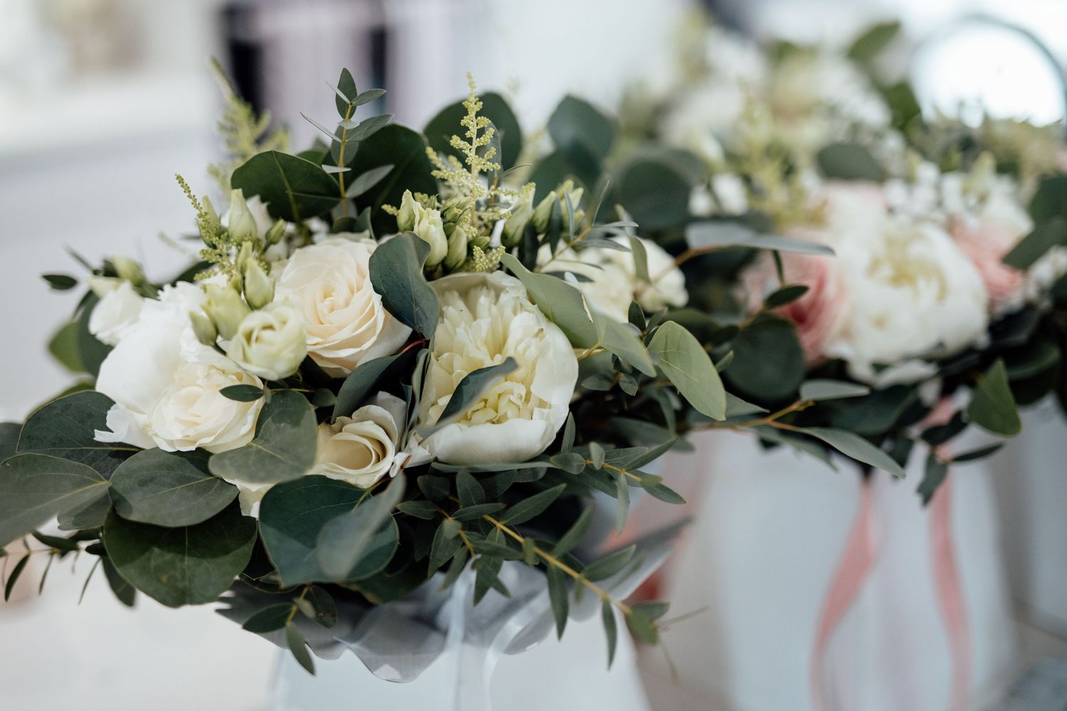 An elegant white floral arrangement with roses and greenery for a wedding.