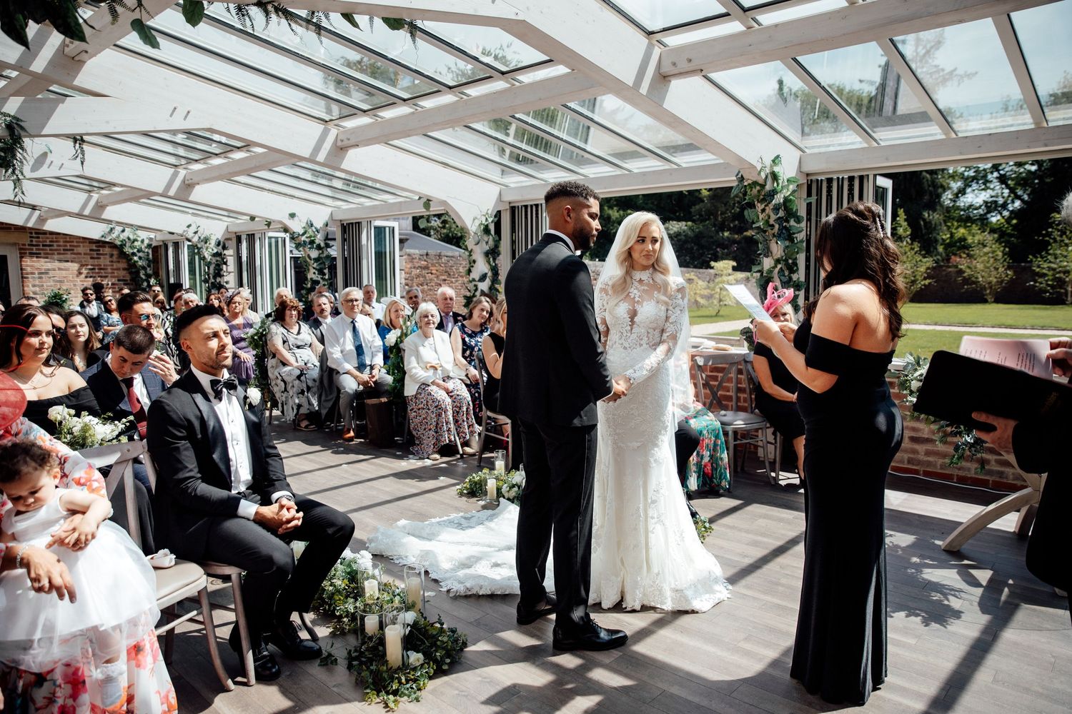 Wedding ceremony taking place under a glass conservatory roof.
