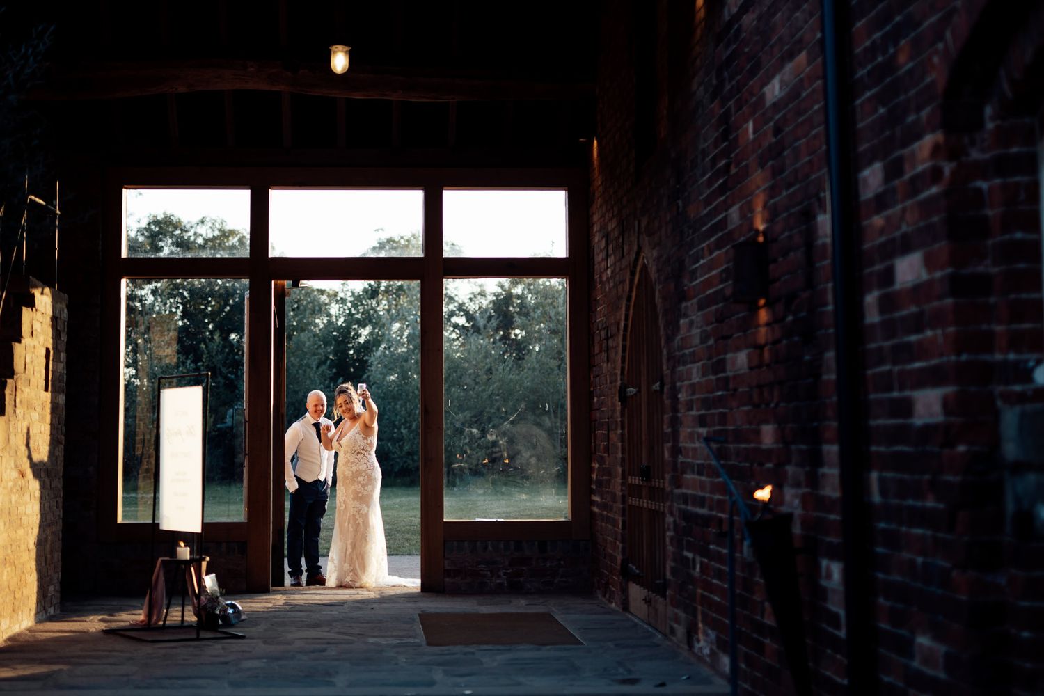 Silhouette of couple in doorway against sunset through industrial brick venue.